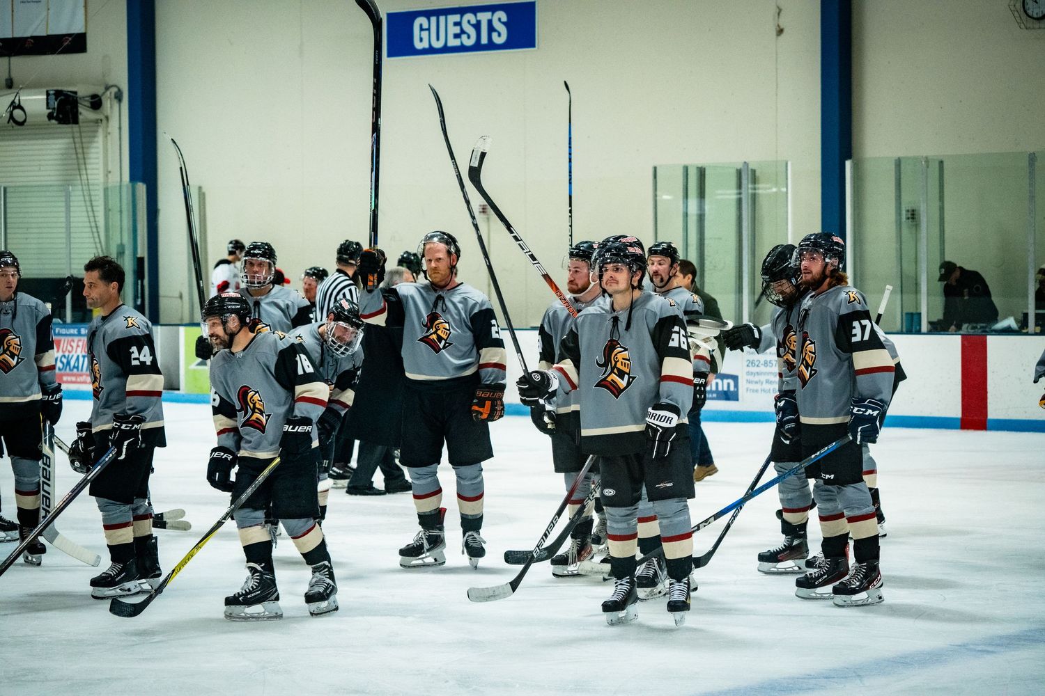 Wide view of hockey players practicing formations on indoor ice rink.