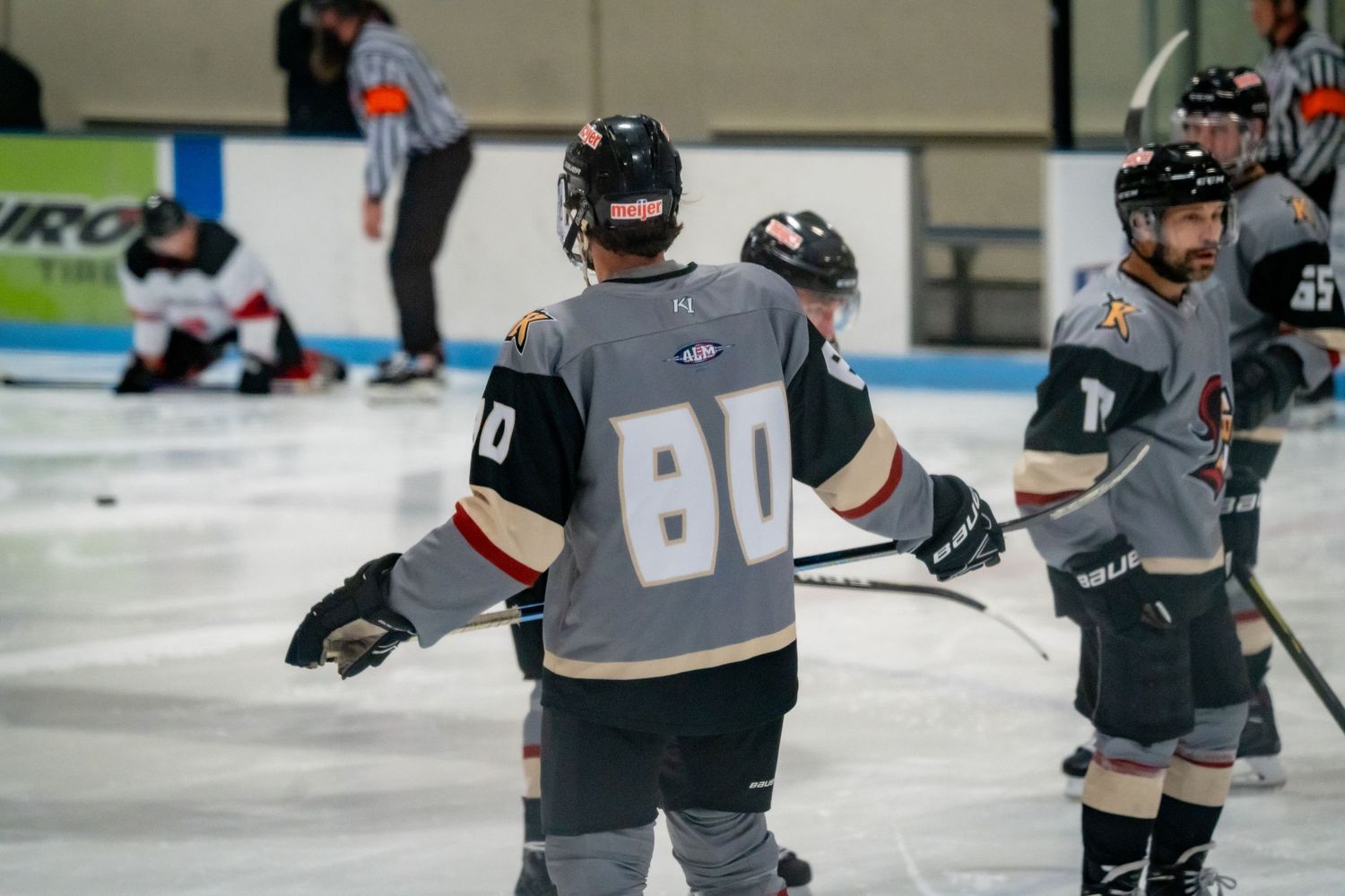 Hockey players in black and gray jerseys compete for the puck during an intense ice hockey match.