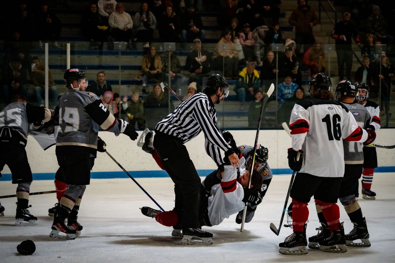 Ice hockey players compete for puck control during intense game action.