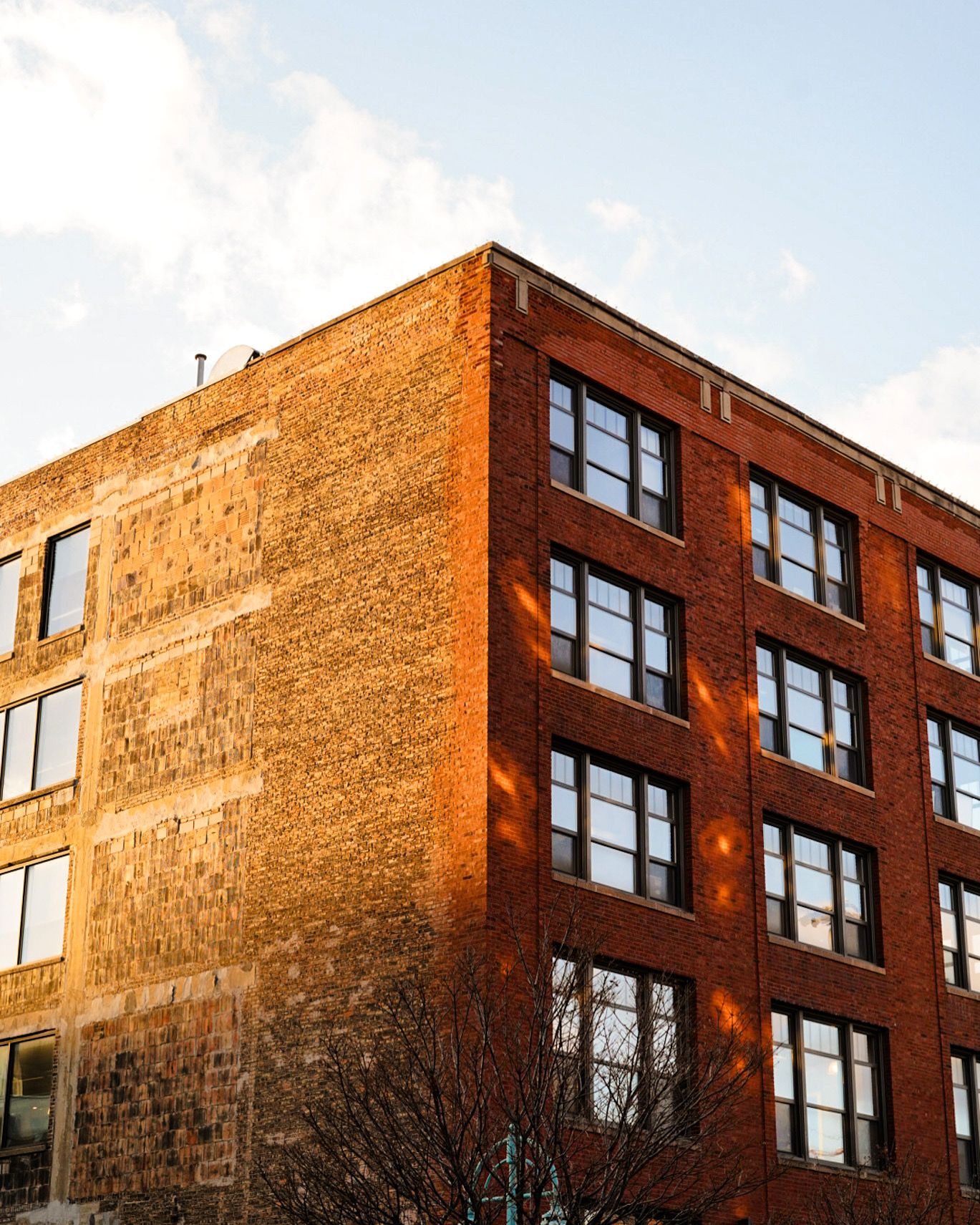 Brick apartment building exterior with rows of windows glowing in warm sunlight.
