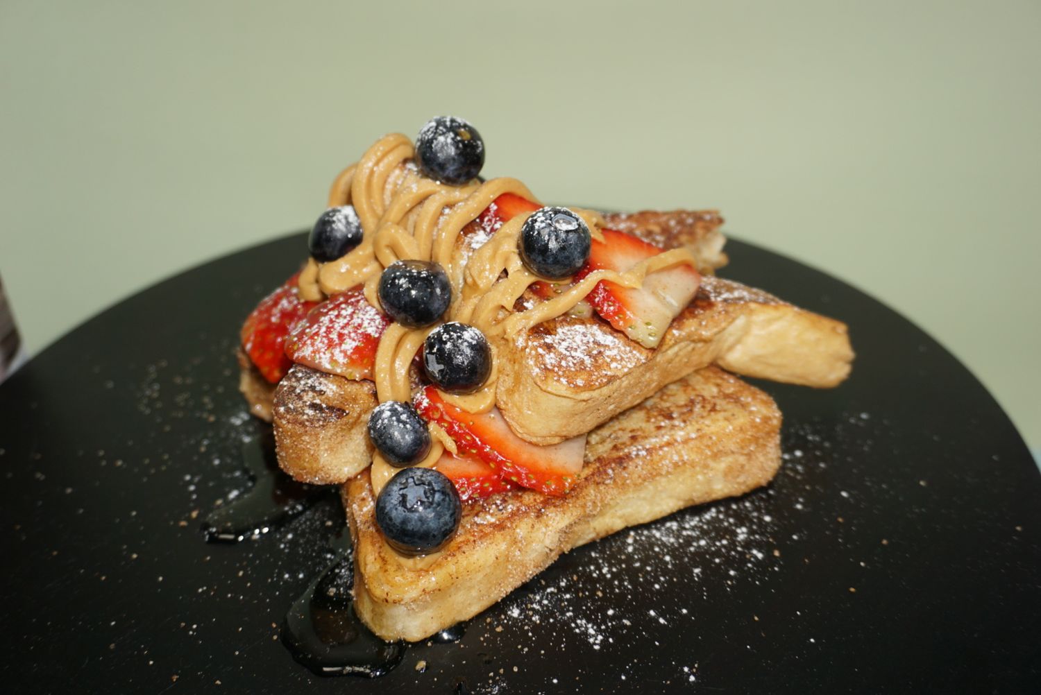 French toast slices garnished with blueberries, strawberries and powdered sugar.