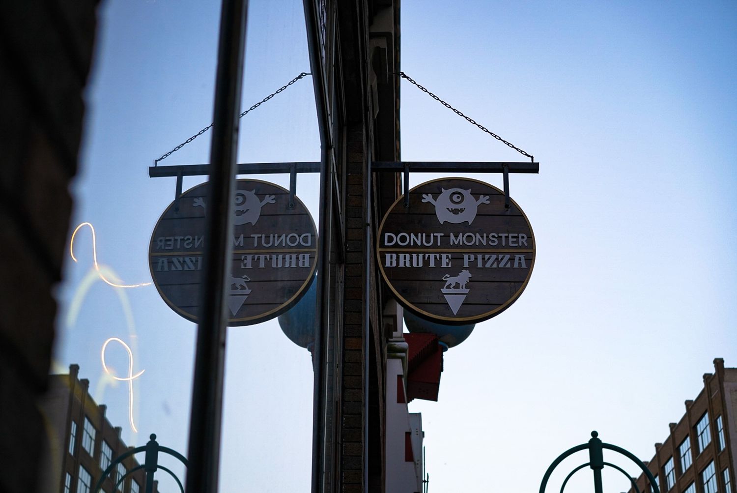 Urban street signs and poles silhouetted against a bright blue sky.