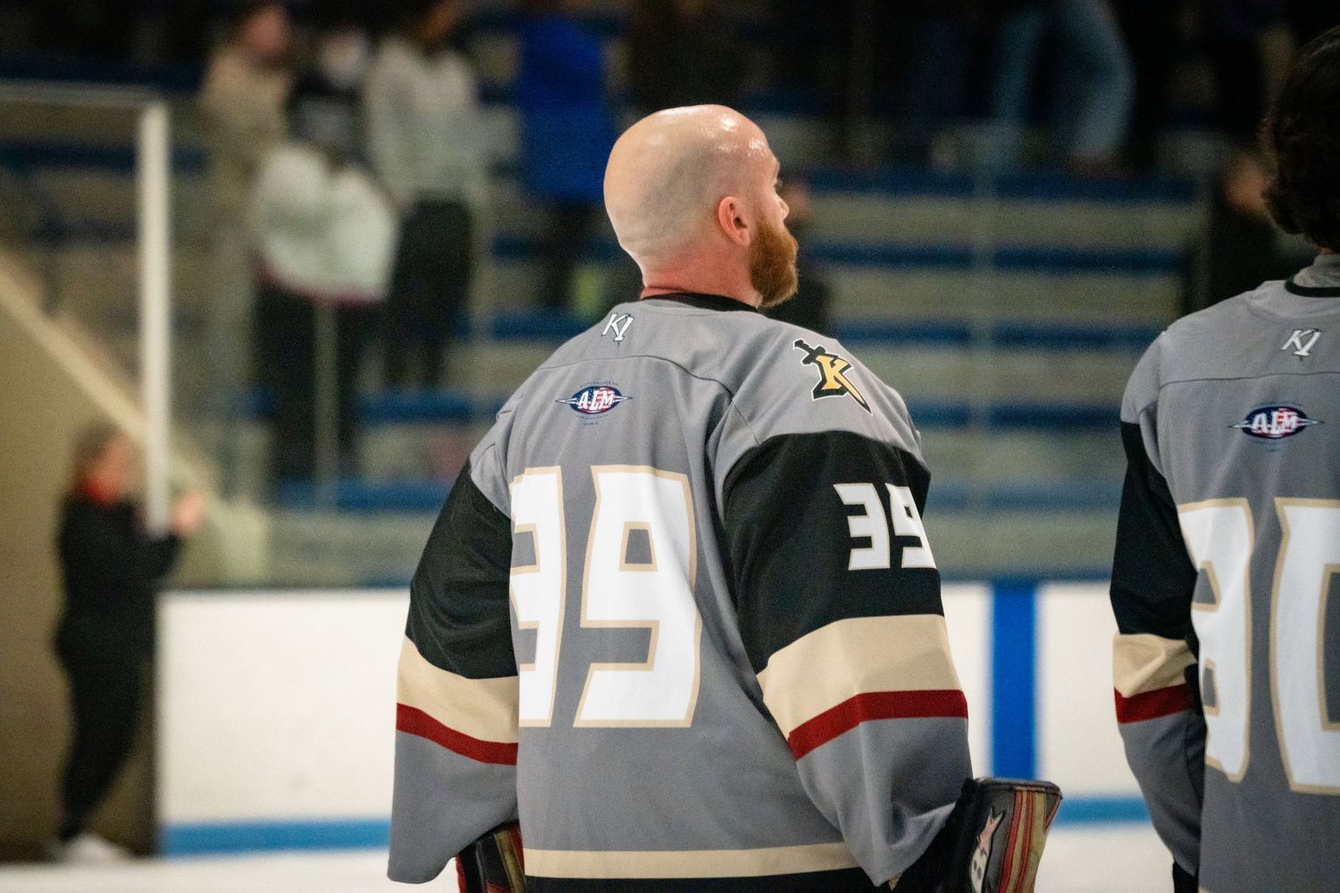 Hockey players in dark and light jerseys face off during an indoor ice hockey game.