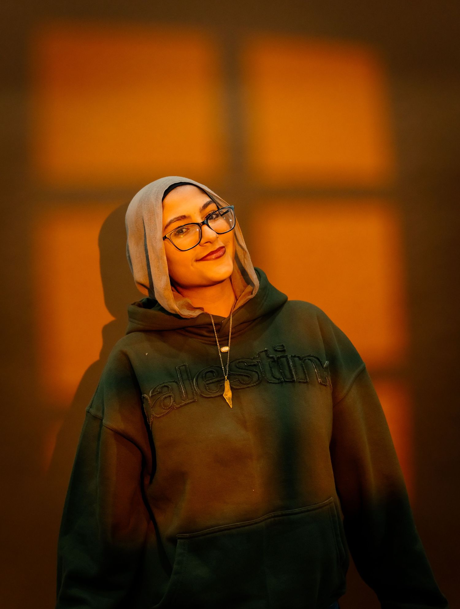 A person in a dark hoodie and glasses shown in a sequence of photos with warm orange lighting and shadows.
