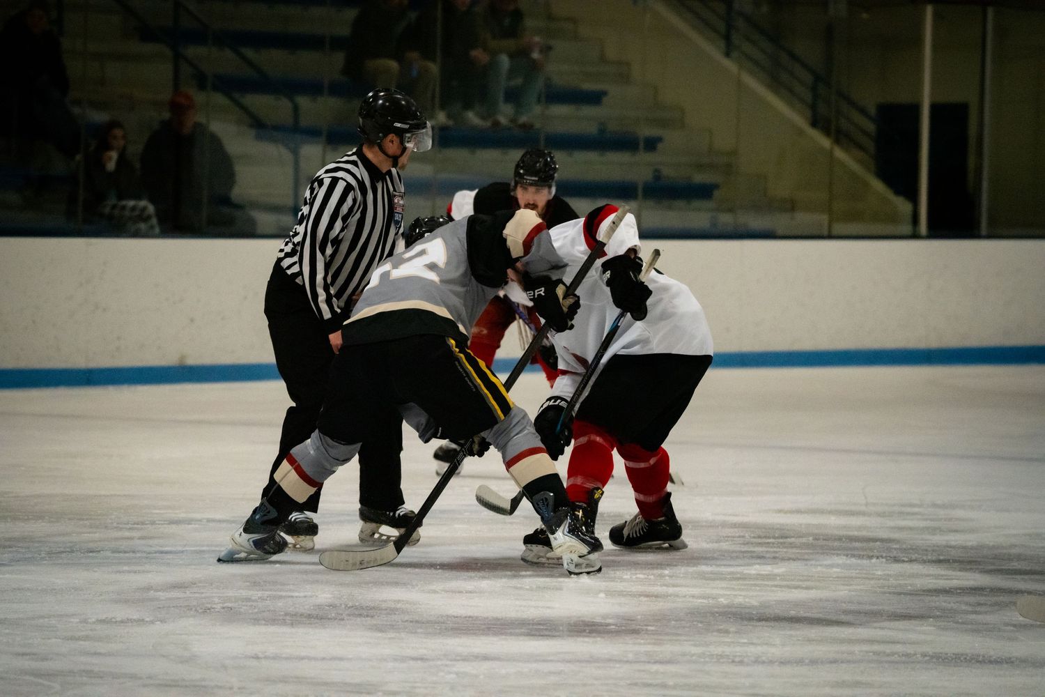 Players position themselves around the referee during a hockey game face-off.
