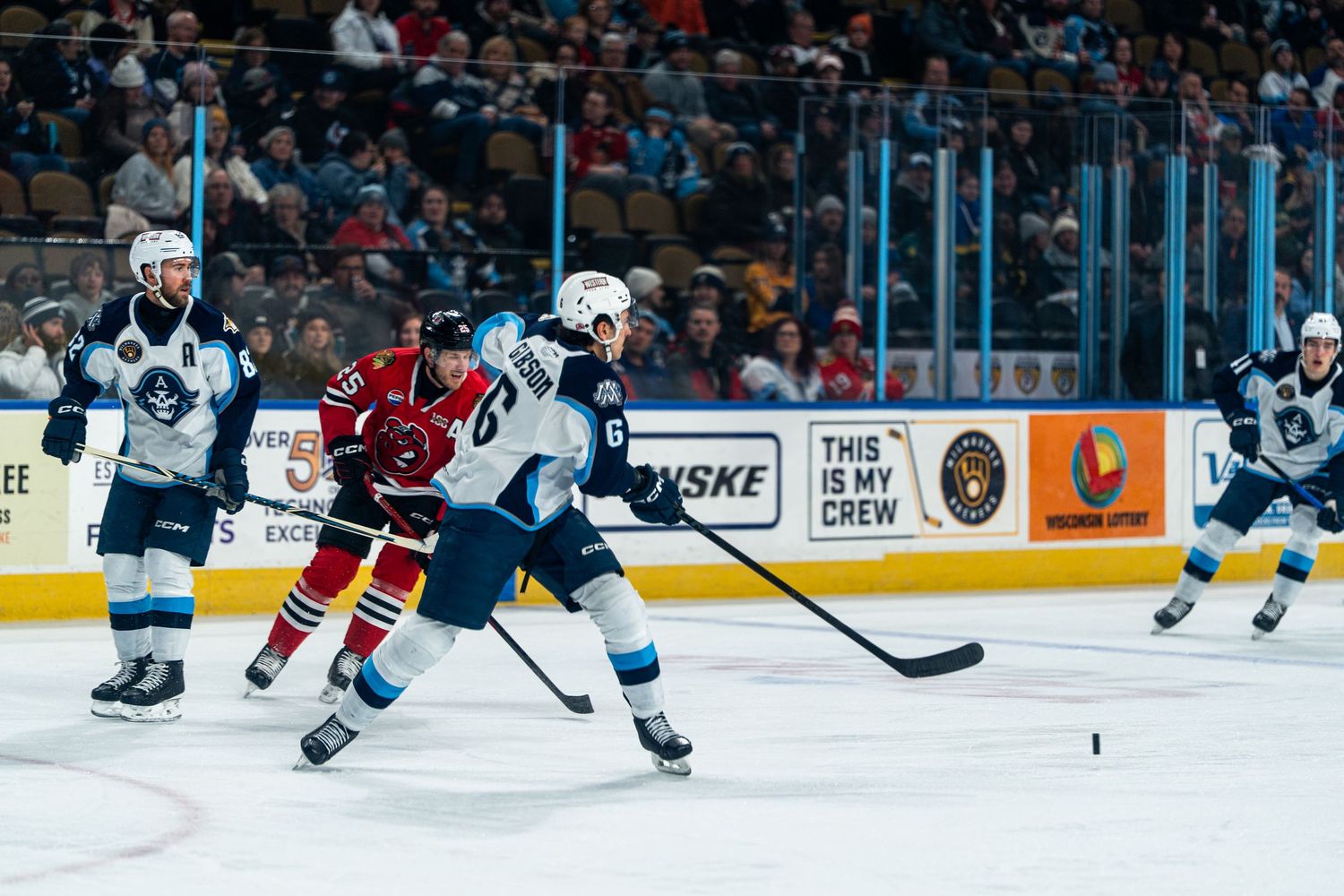 Hockey players from opposing teams battle for puck control during intense game action.