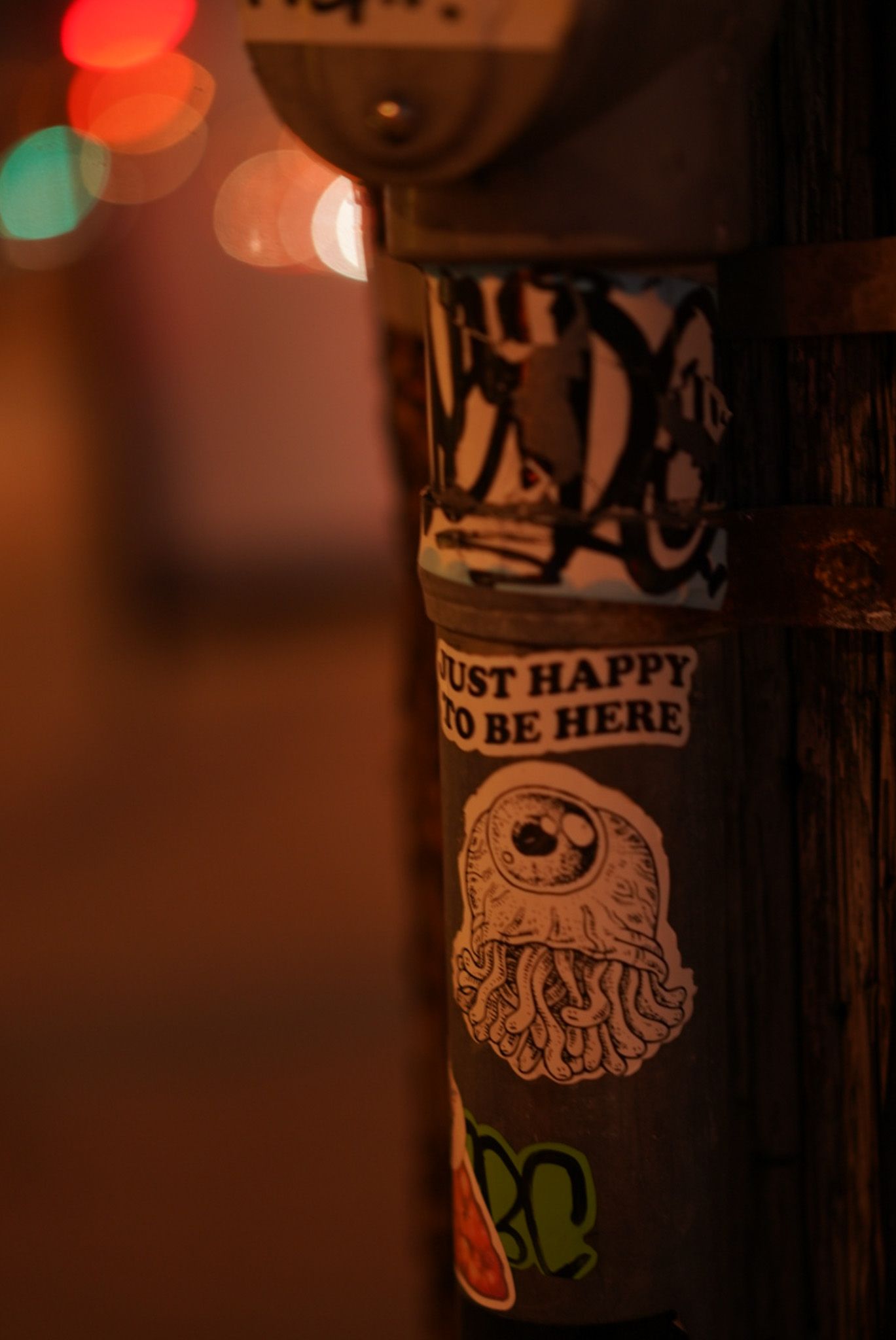 Close-up of a dark lamppost with decorative label in dim lighting.