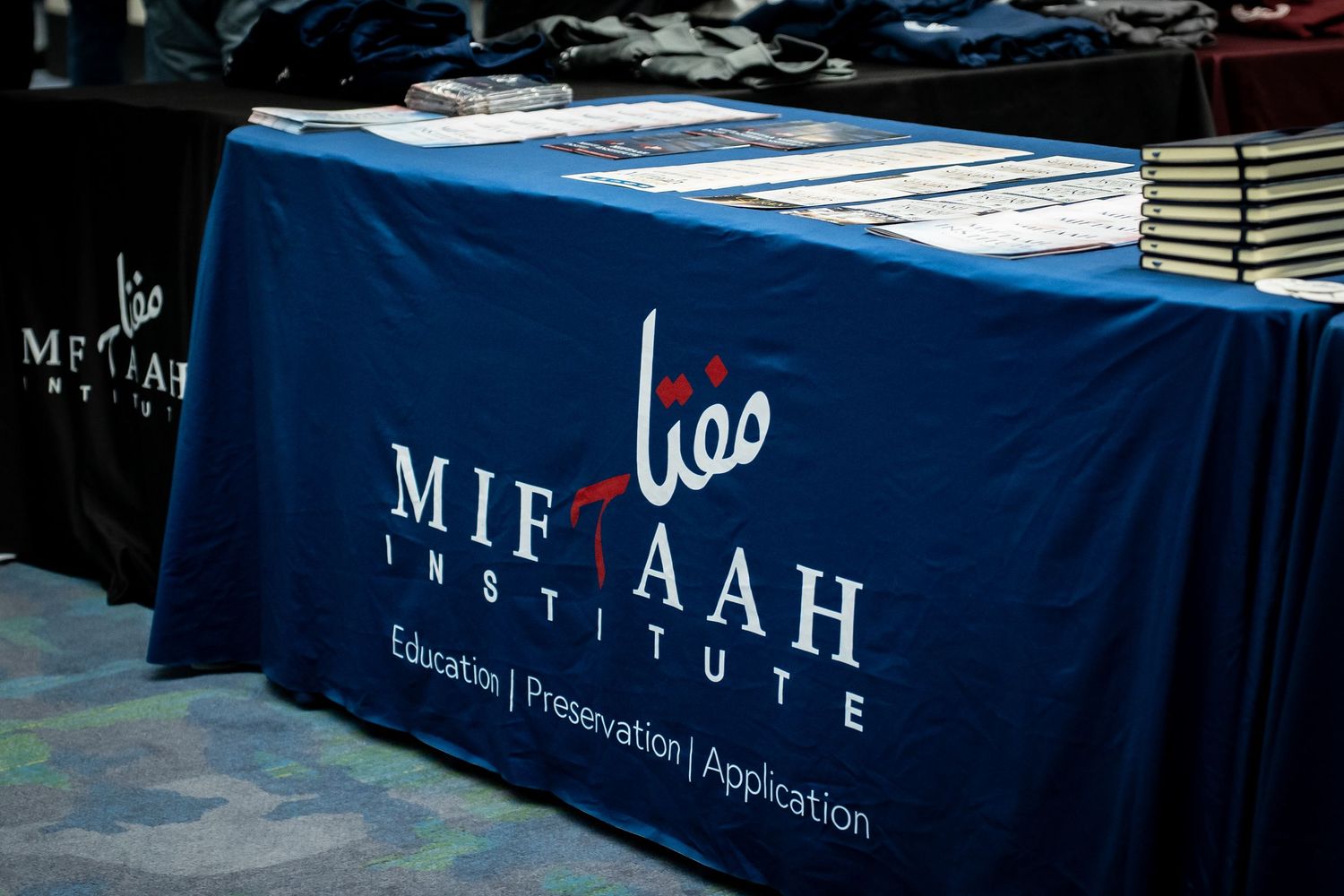 A row of navy blue tablecloths with white text logos displayed at what appears to be a conference or event setup.