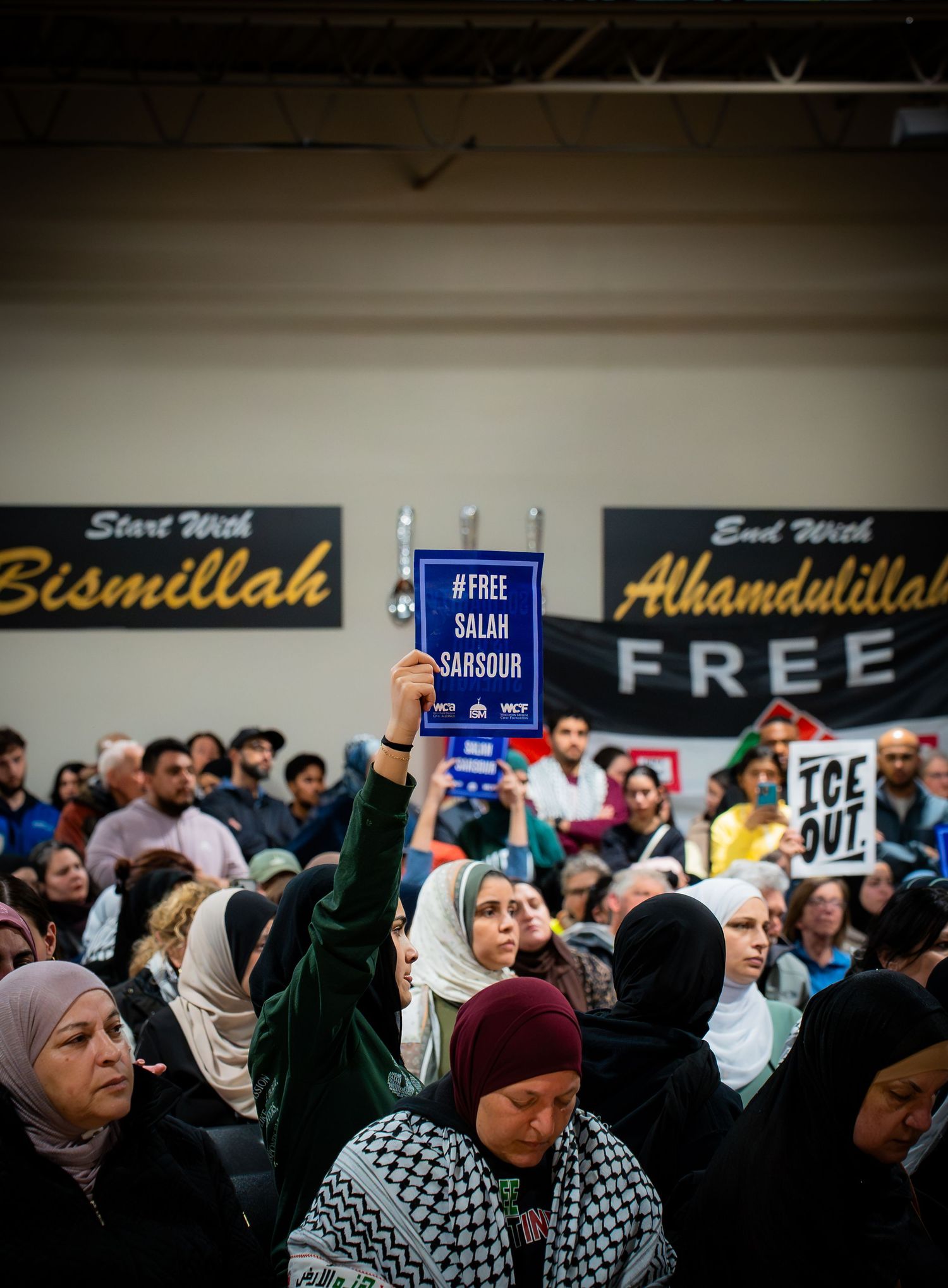 Crowd at Muslim community rally holding #FreeSalahSarsour sign, with Bismillah and Alhamdulillah banners visible.