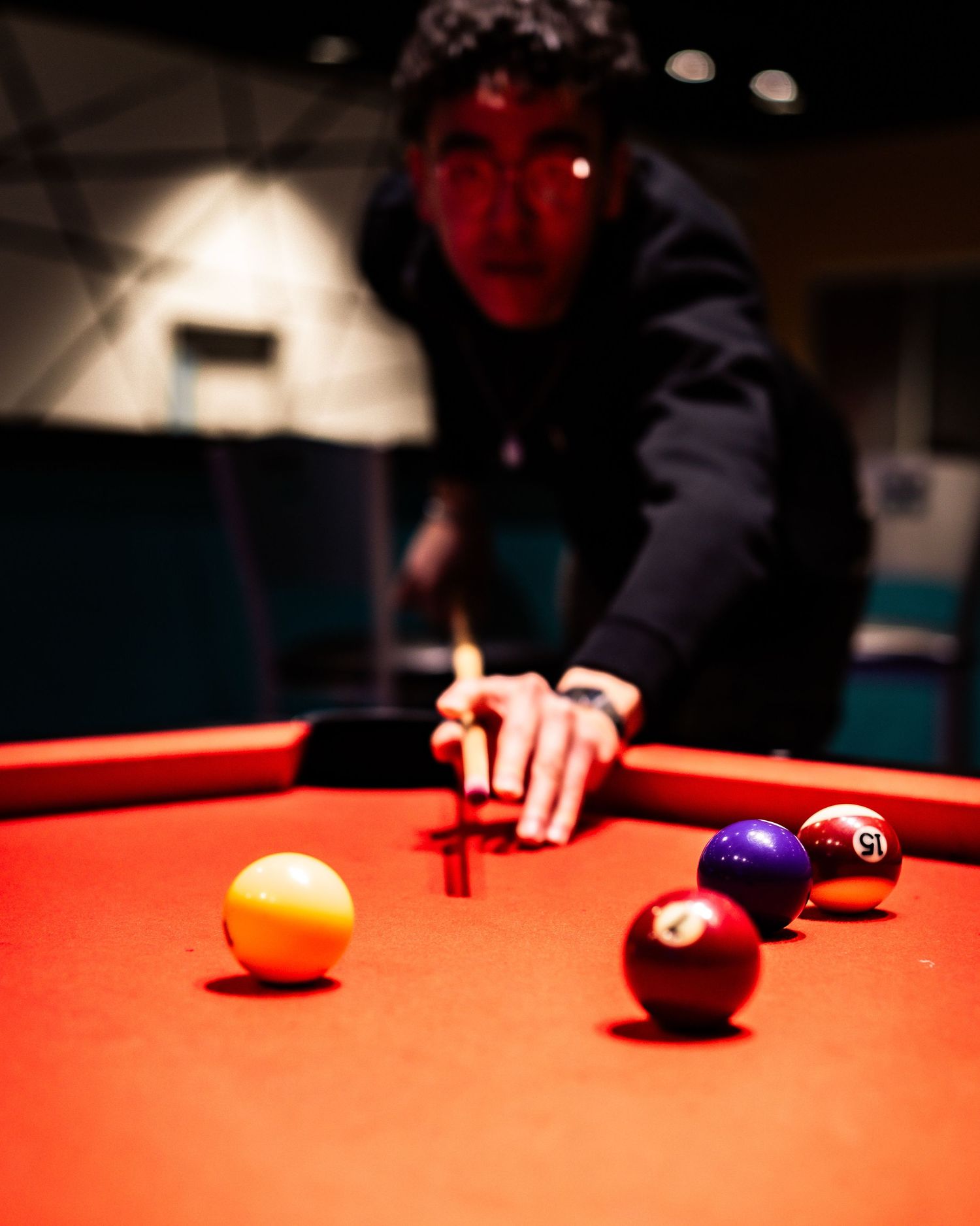 Pool table with colorful billiard balls scattered across red felt surface.