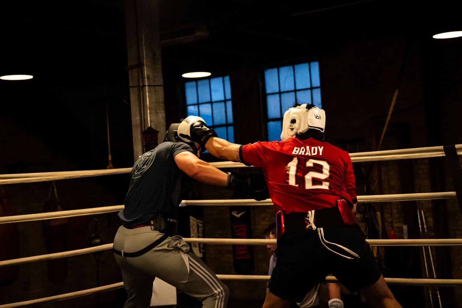 Boxing training session underway with fighters practicing in a professional ring setting.