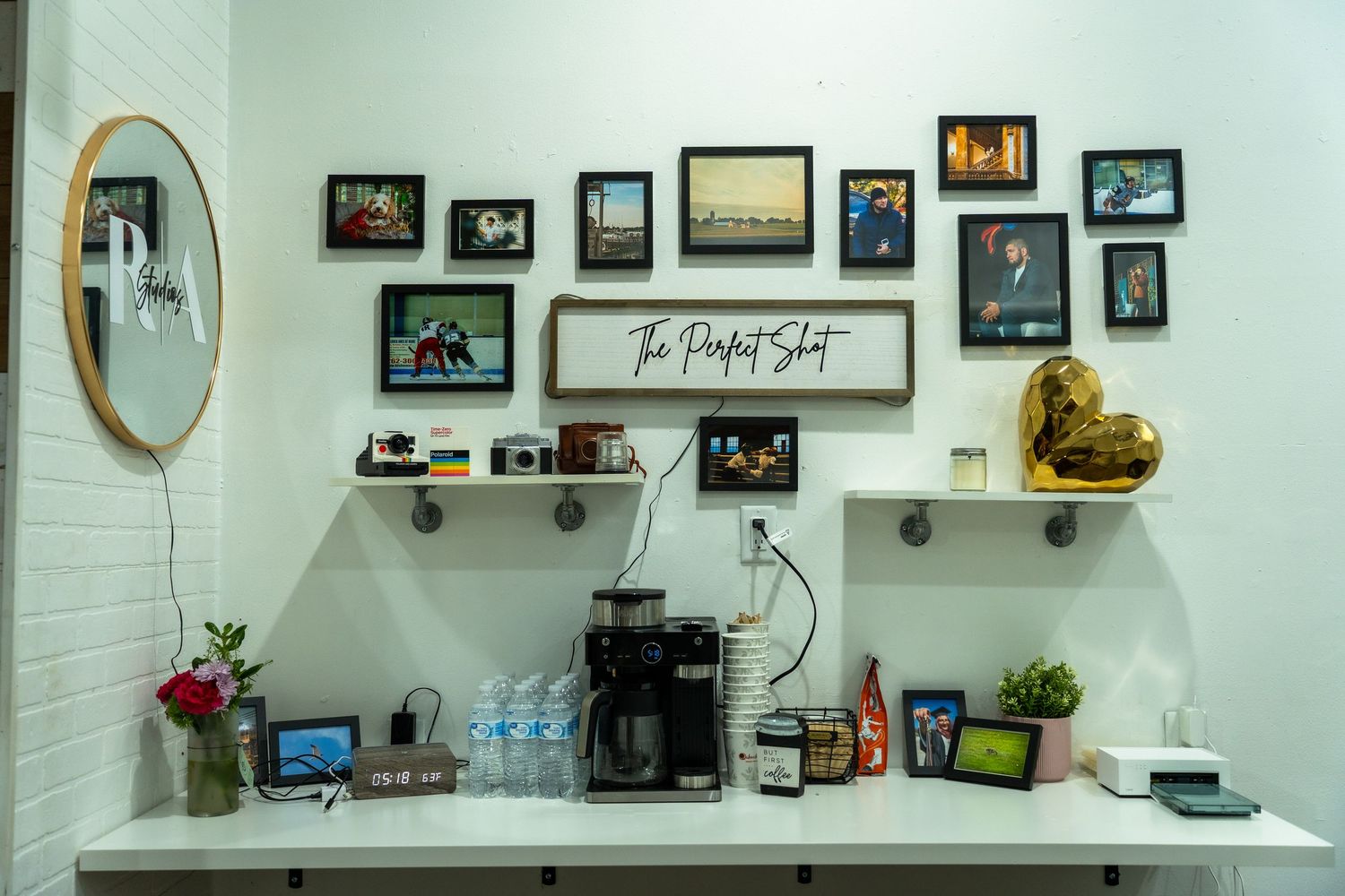 A gallery wall display with framed photos and artwork arranged along a light-colored wall with decorative accents.