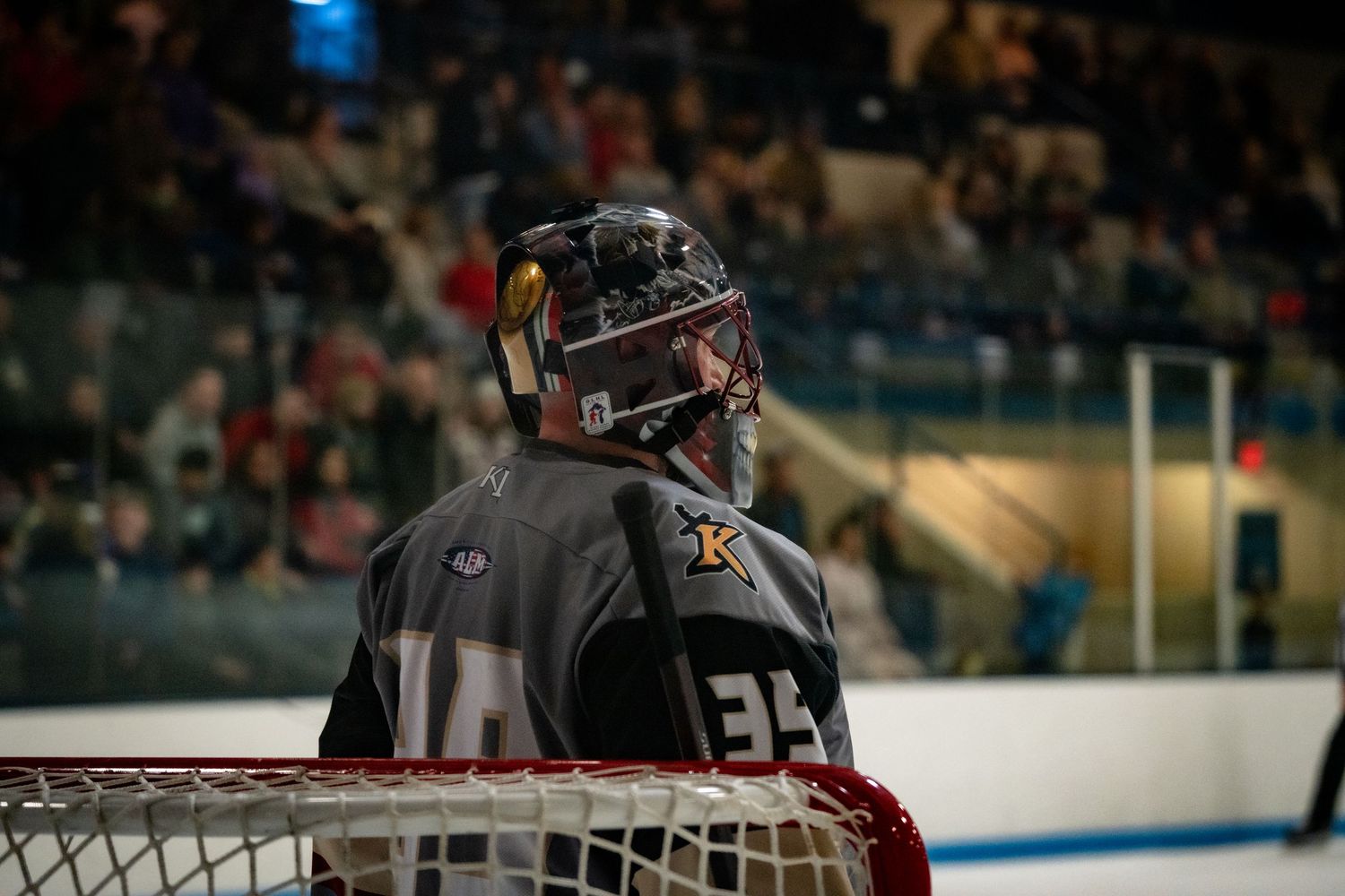 Hockey goalie in dark jersey stands ready at the net during a game.