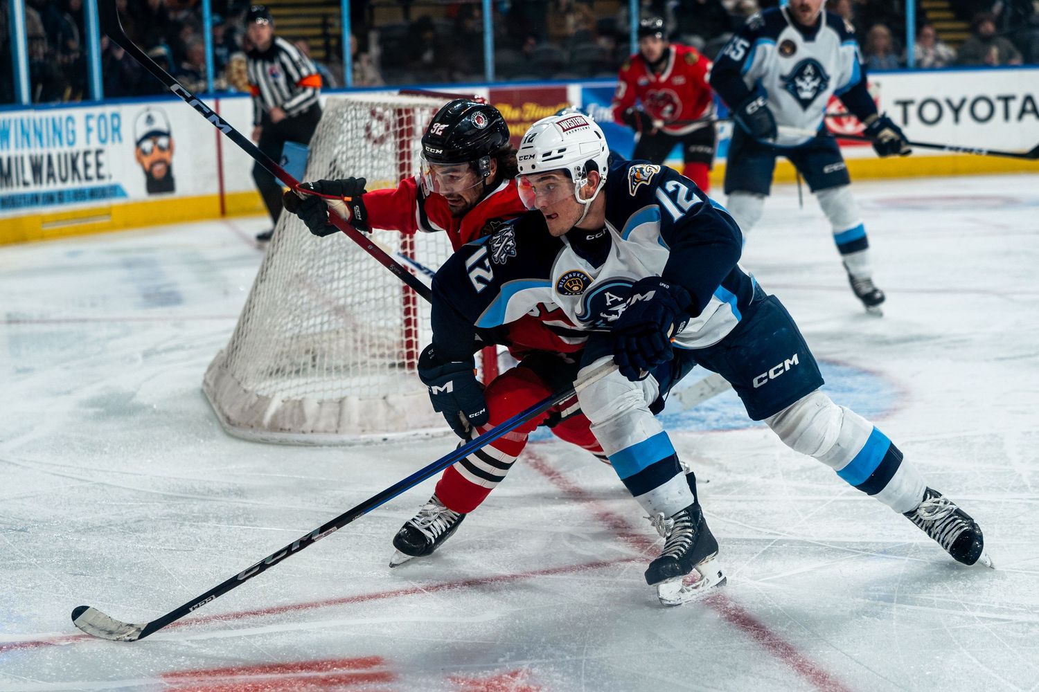 Two hockey players battle for puck control near the goal during game.