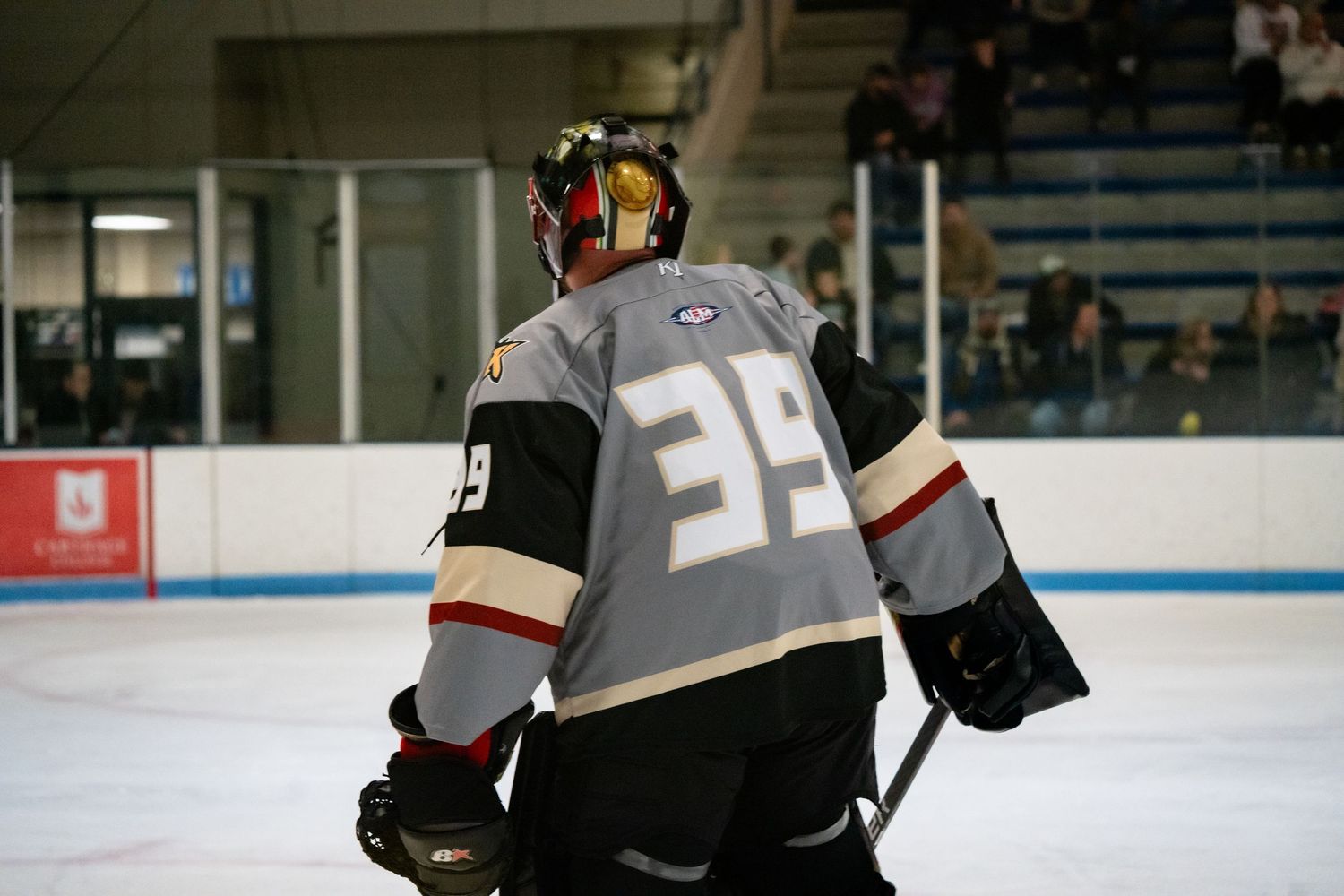 Hockey players in gray jerseys practicing drills on an ice rink.