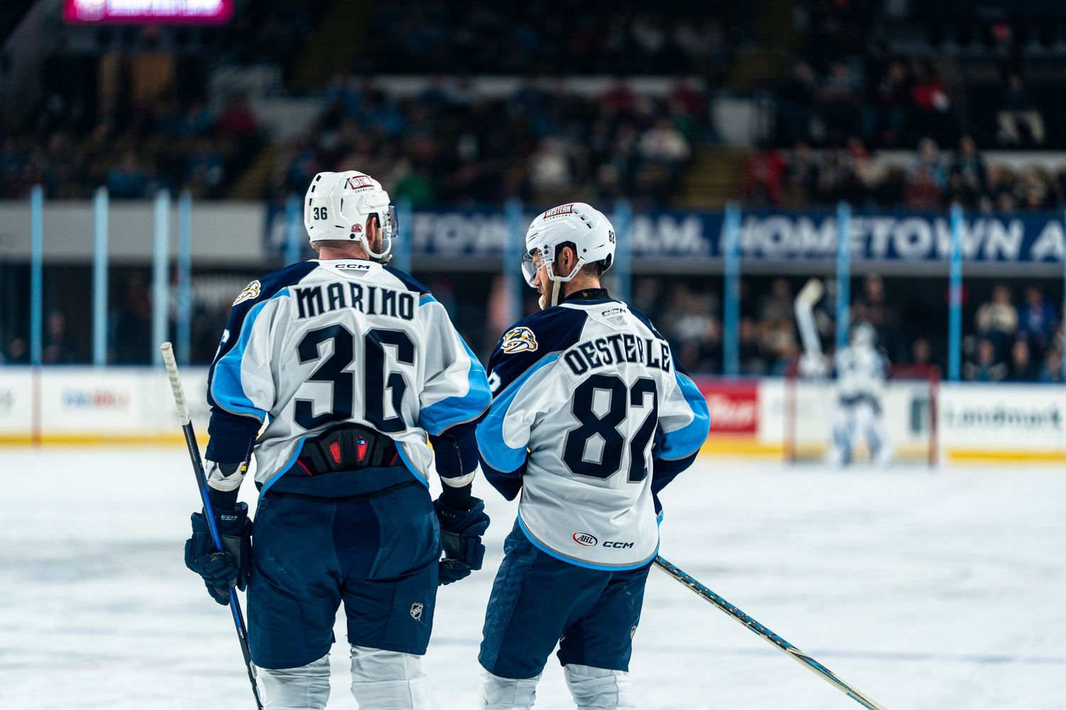 Players in white and blue jerseys skate during a professional hockey match.