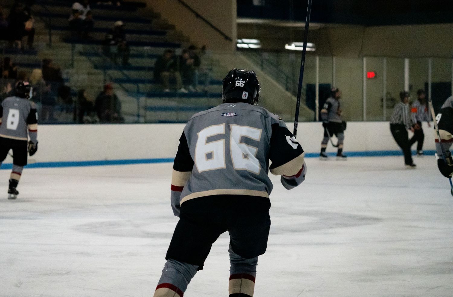 Ice hockey players compete on a rink during an intense match with one player taking a shot on goal.