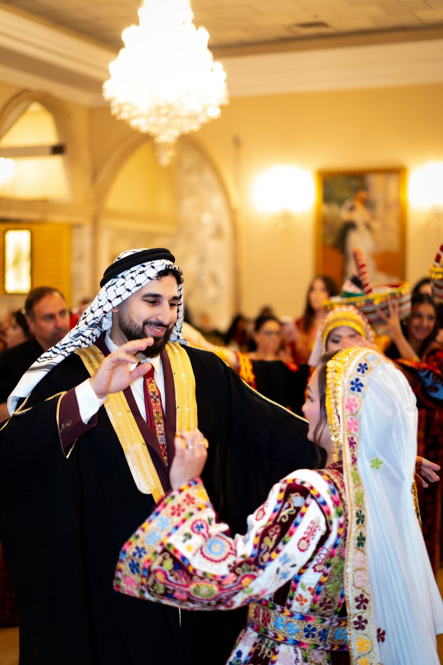 Festive celebration with traditional Middle Eastern dance and colorful attire in an elegant ballroom.