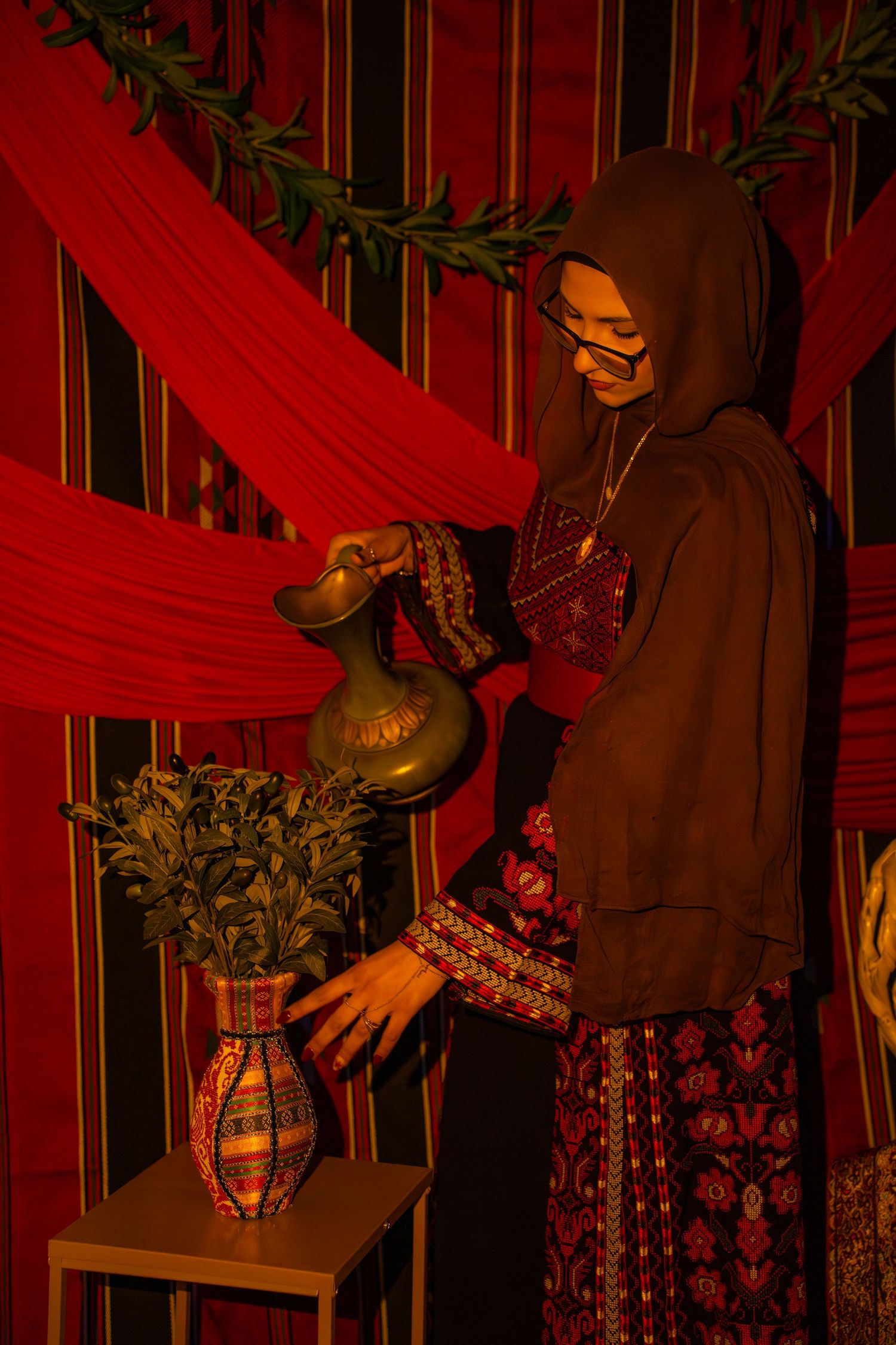 A series of red-tinted photos showing someone arranging decorative lanterns and greenery against a dark background.