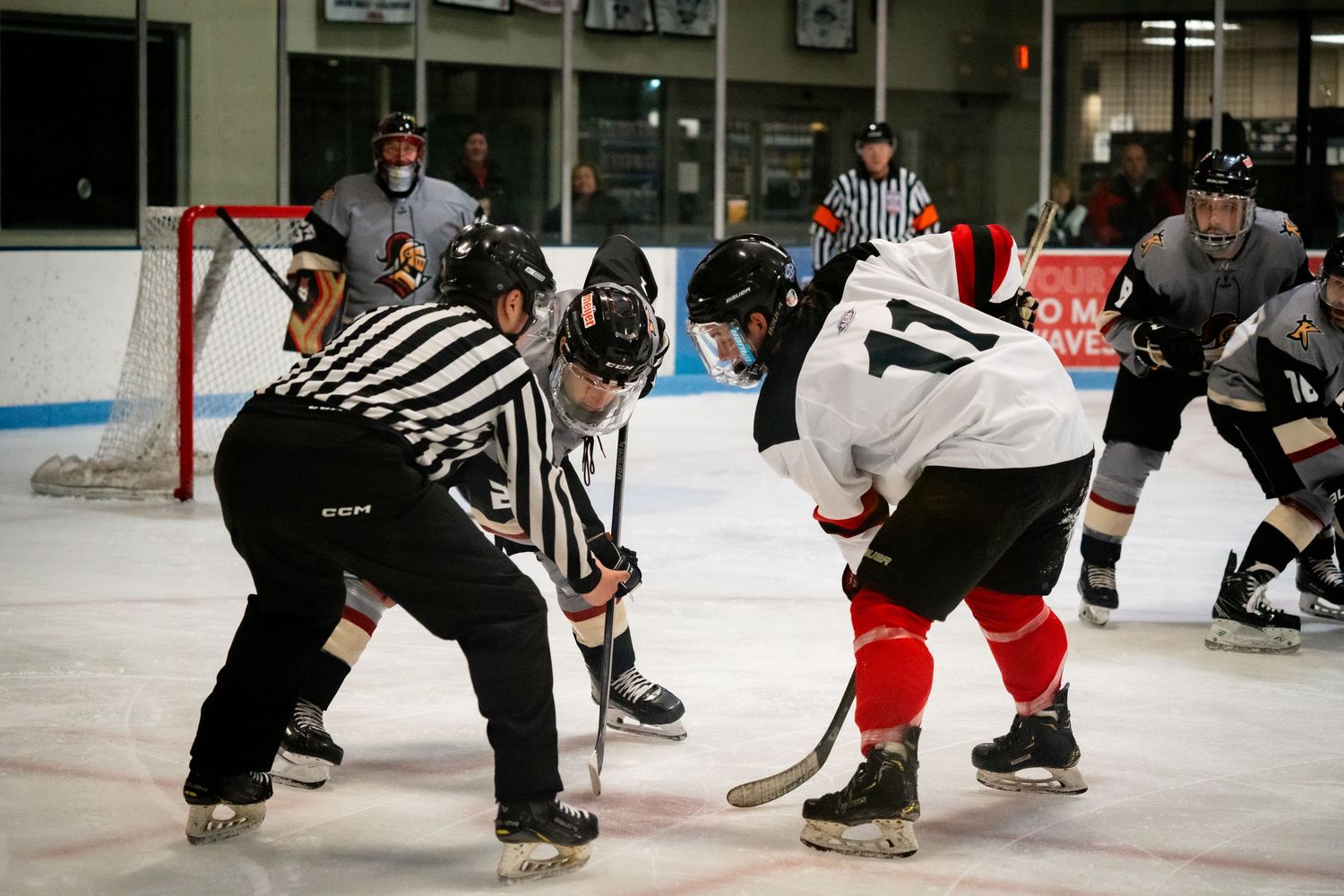 Ice hockey players gather around the referee for a face-off on the rink.