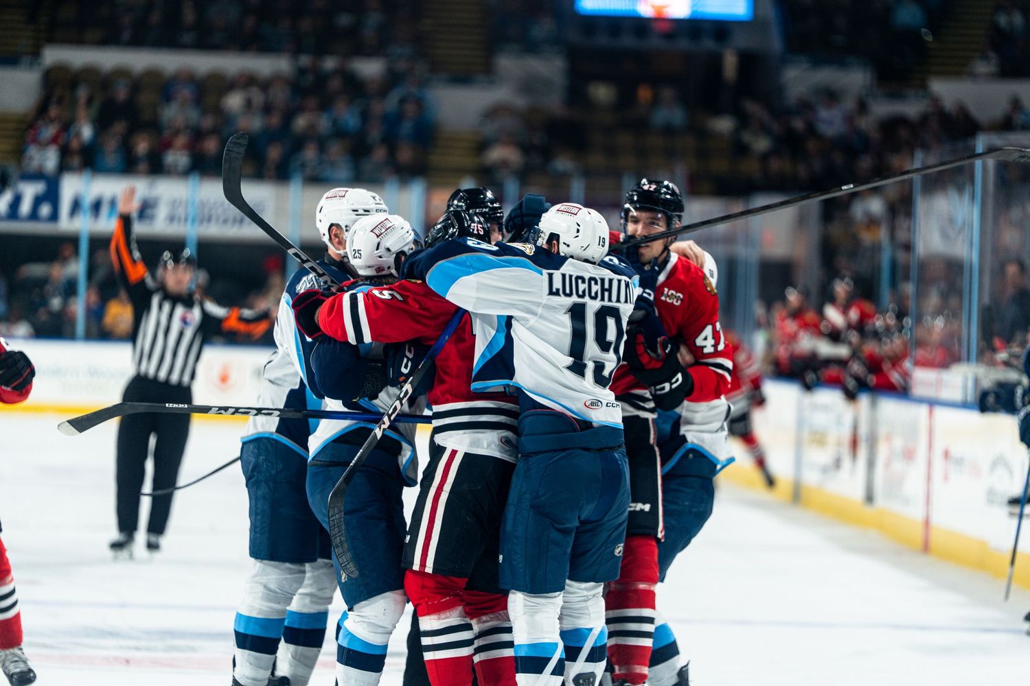 Hockey players from opposing teams face off during a competitive match on the ice.