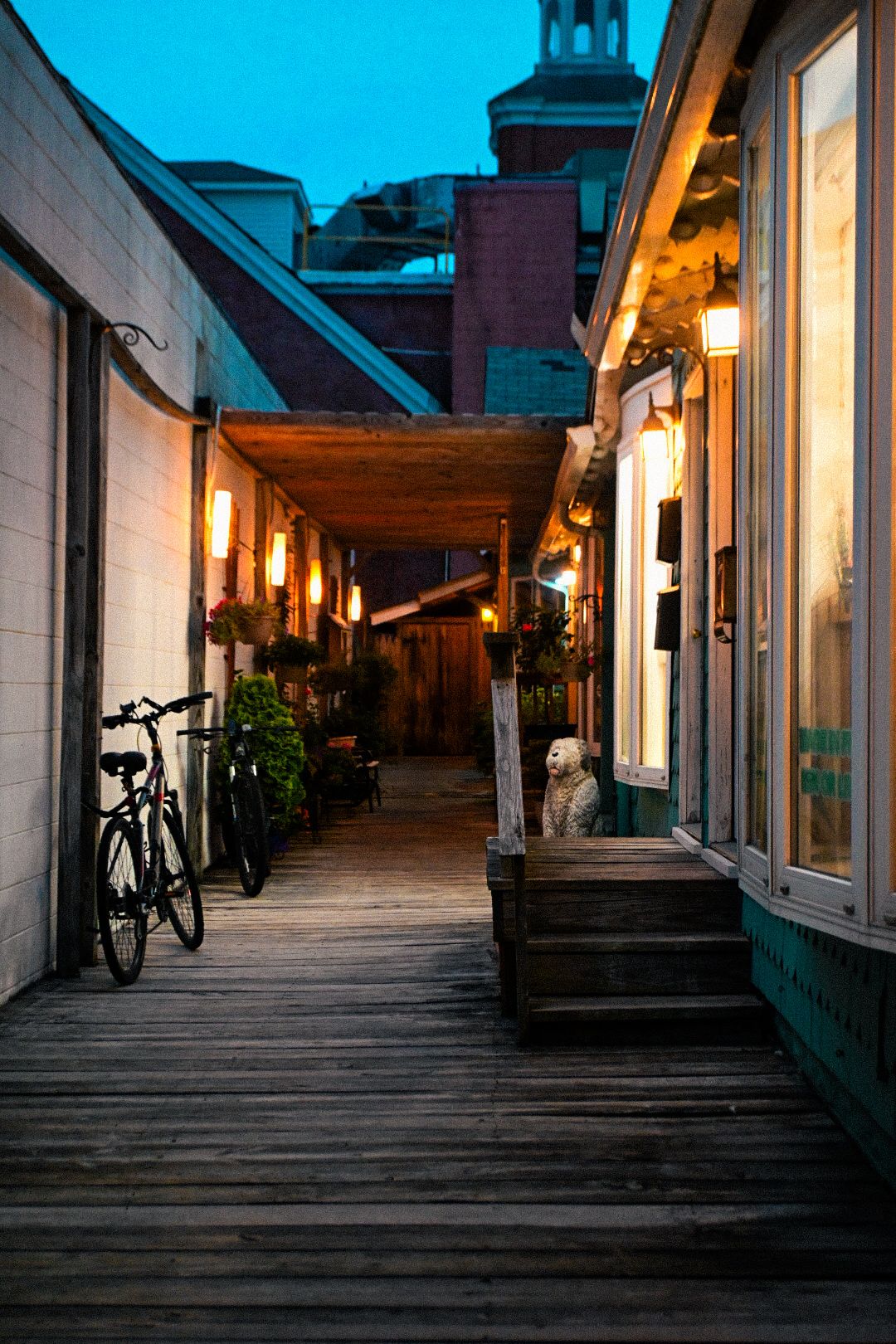 Wooden boardwalk with warm lighting and bicycles at dusk.