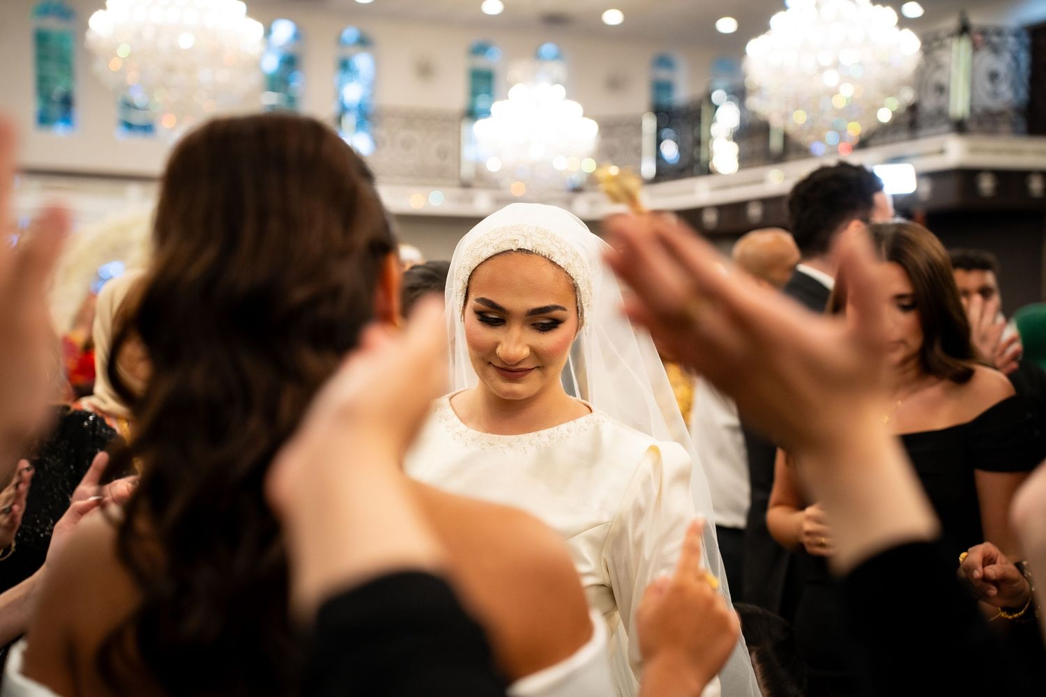 A lively wedding reception with dancing guests and elegant white floral decorations.
