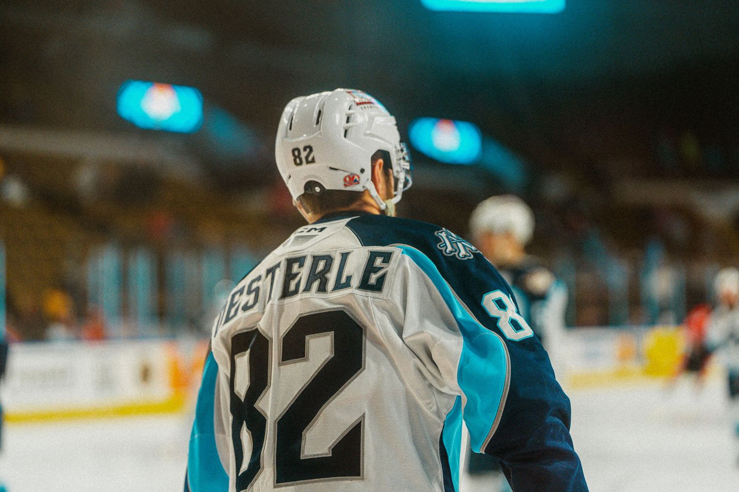Professional hockey player in navy jersey skates with puck during game.