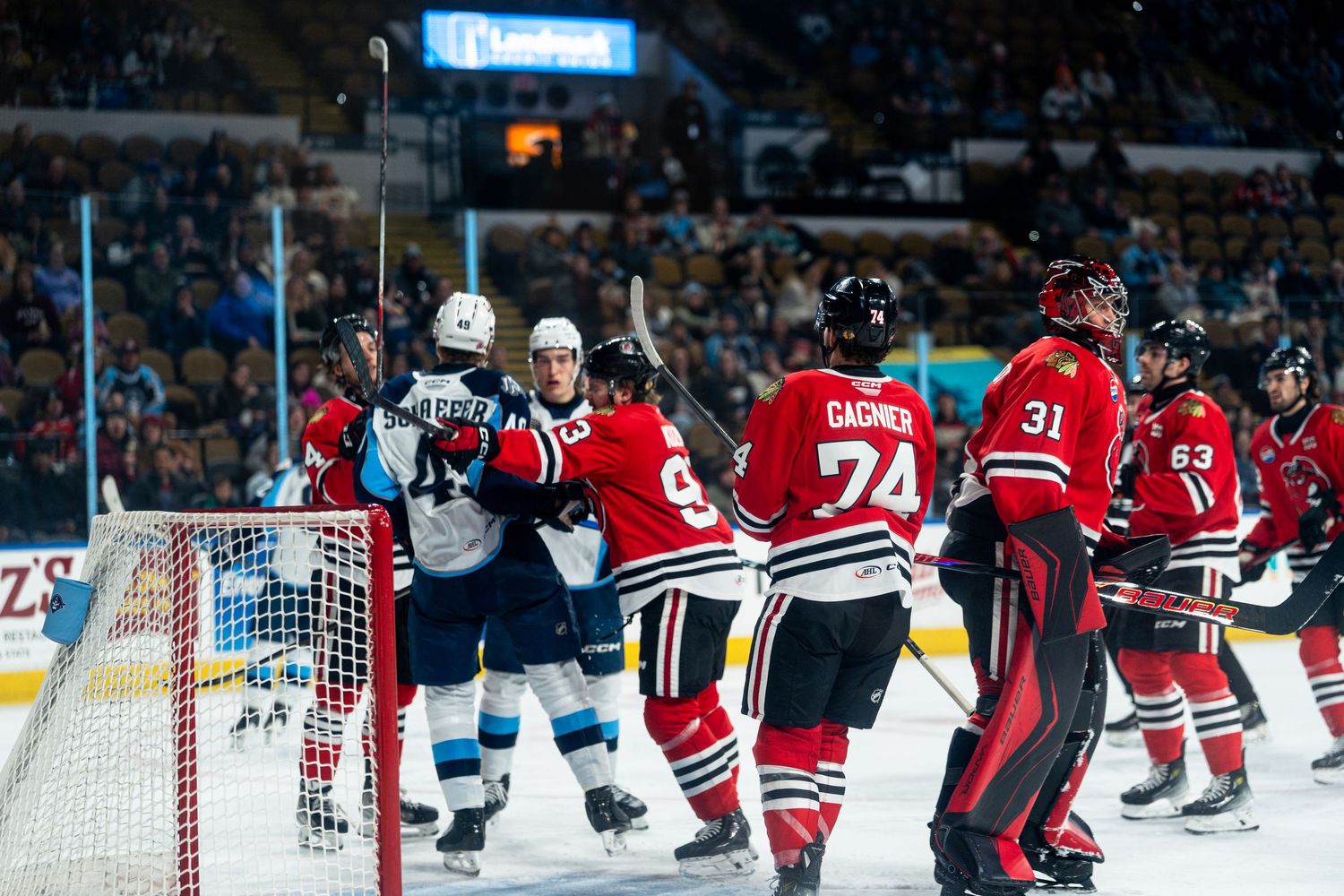Wide view of hockey game showing players and goal net during competitive match.
