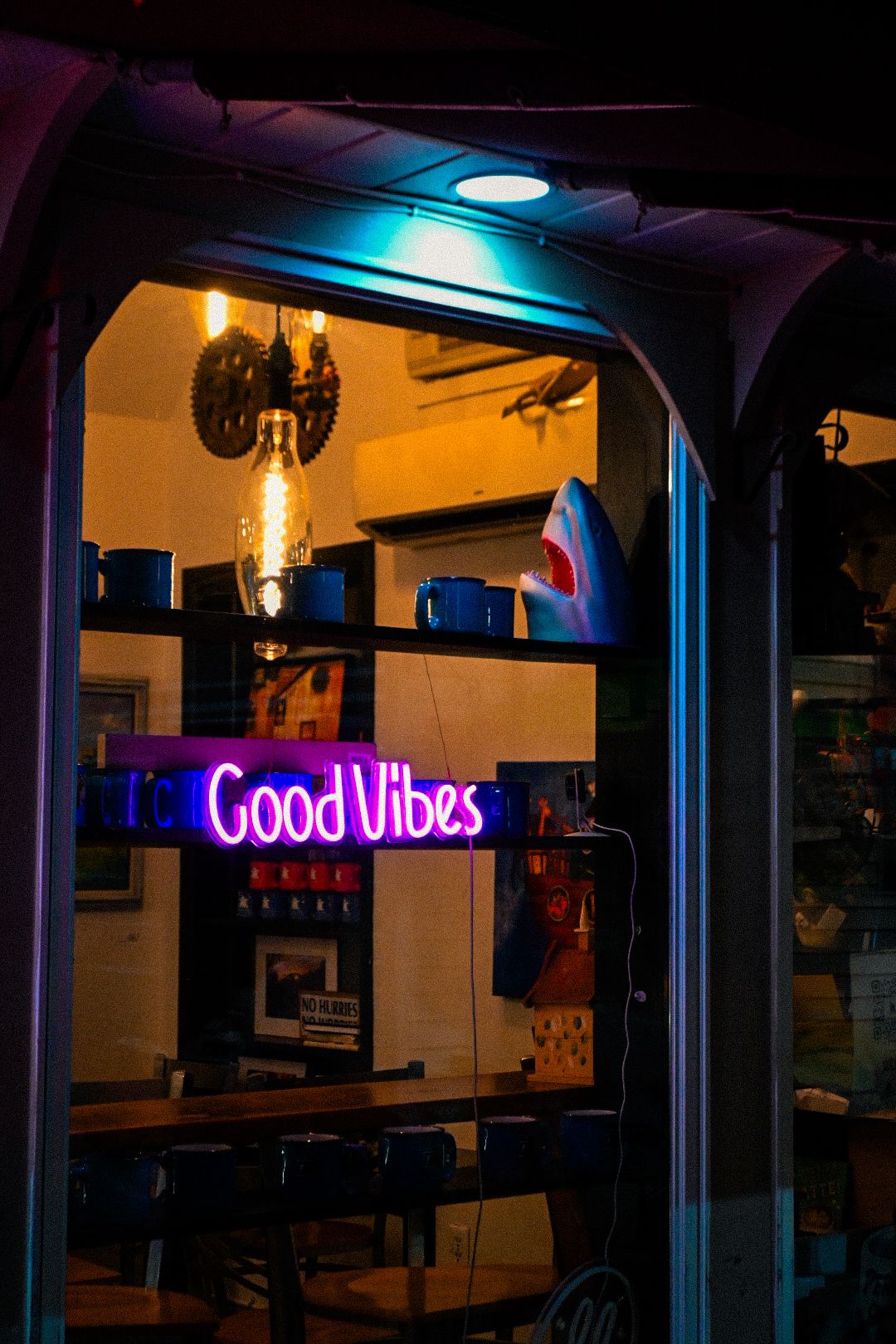 Neon 'Good Vibes' sign glows in dark room with ambient lighting.