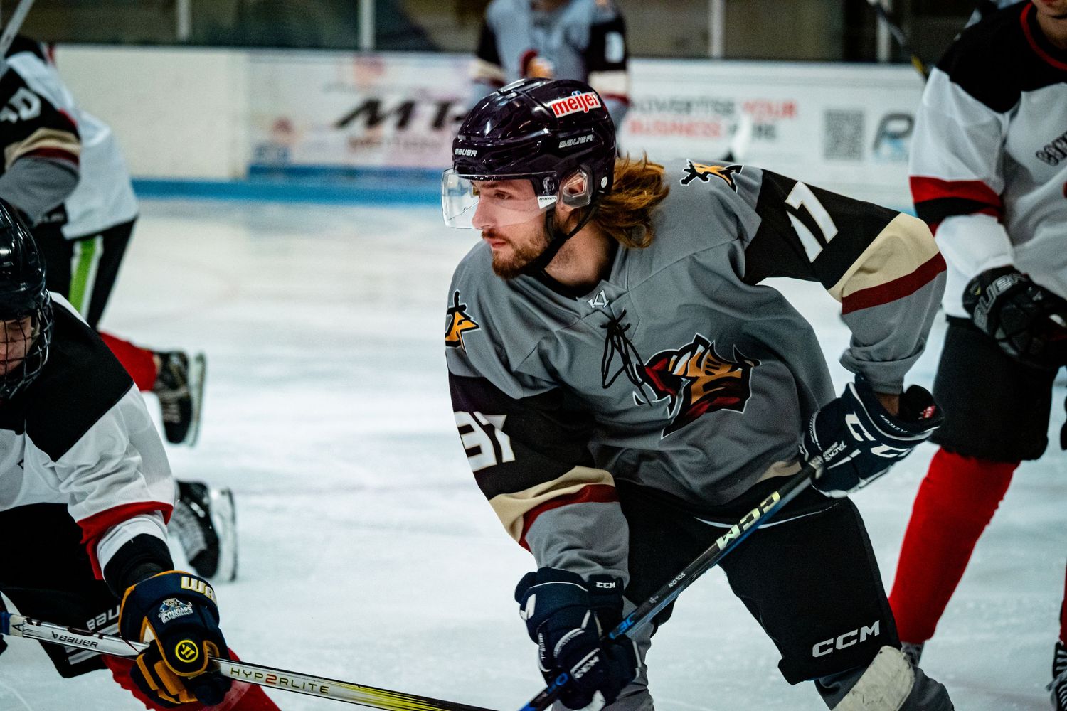 Hockey players in gray jerseys practice drills during team training session.