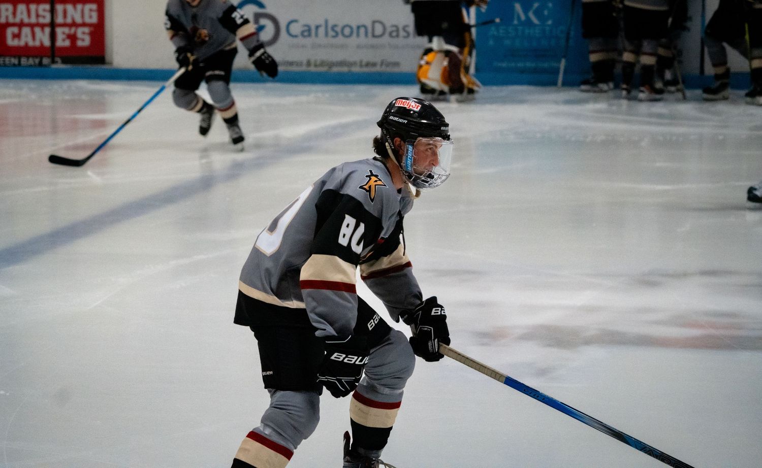 Hockey player in black and white uniform skates on ice during competitive game.
