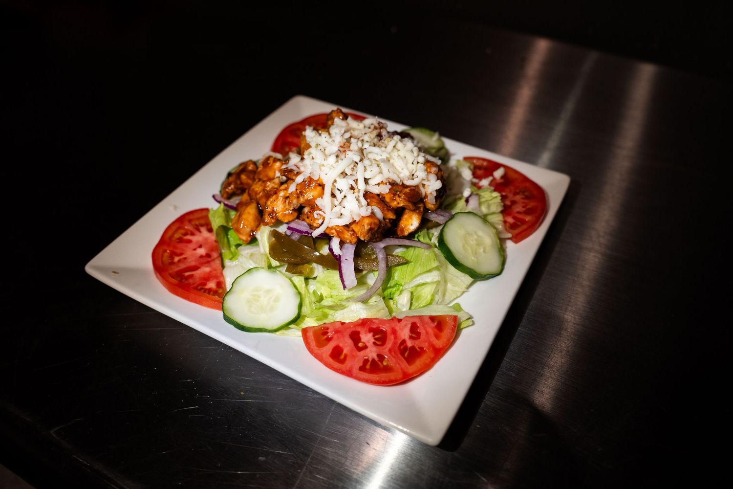 House salad with fresh vegetables and dressing served on white plate.