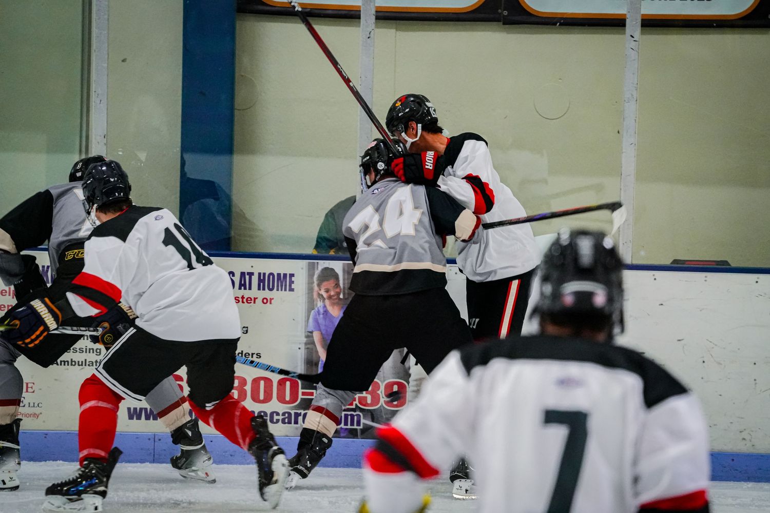 Hockey players battle for position during face-off at center ice.