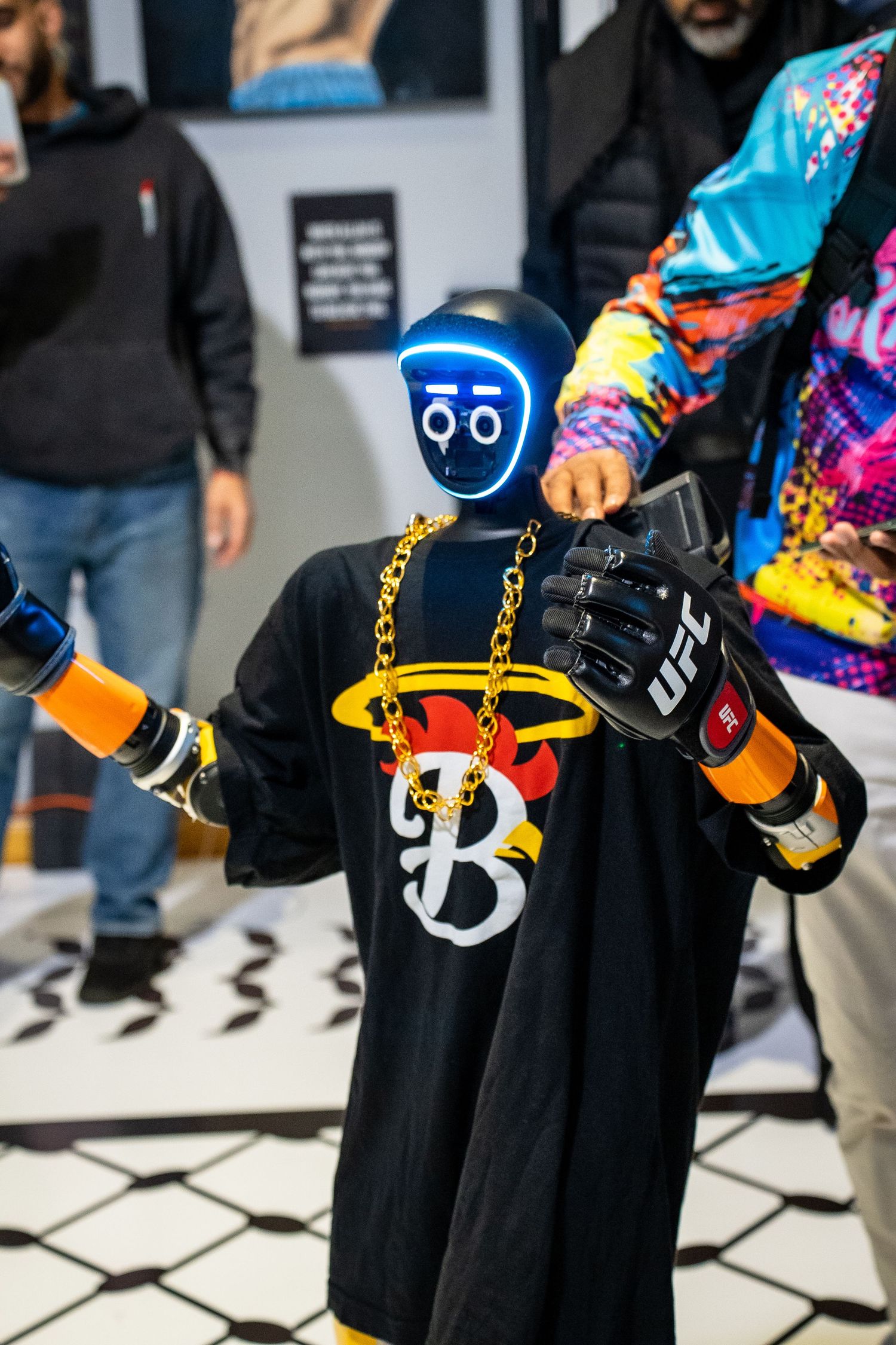 Fashion detail shot showing black outfits accessorized with colorful handbags and gold chain details on a tiled floor.
