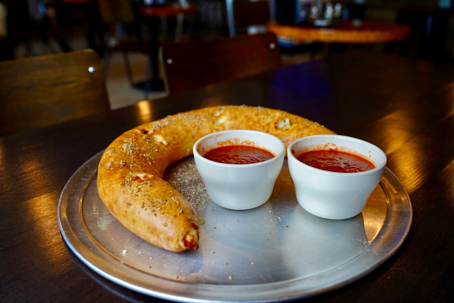 Calzone roll with marinara dipping sauce served on a metal plate.