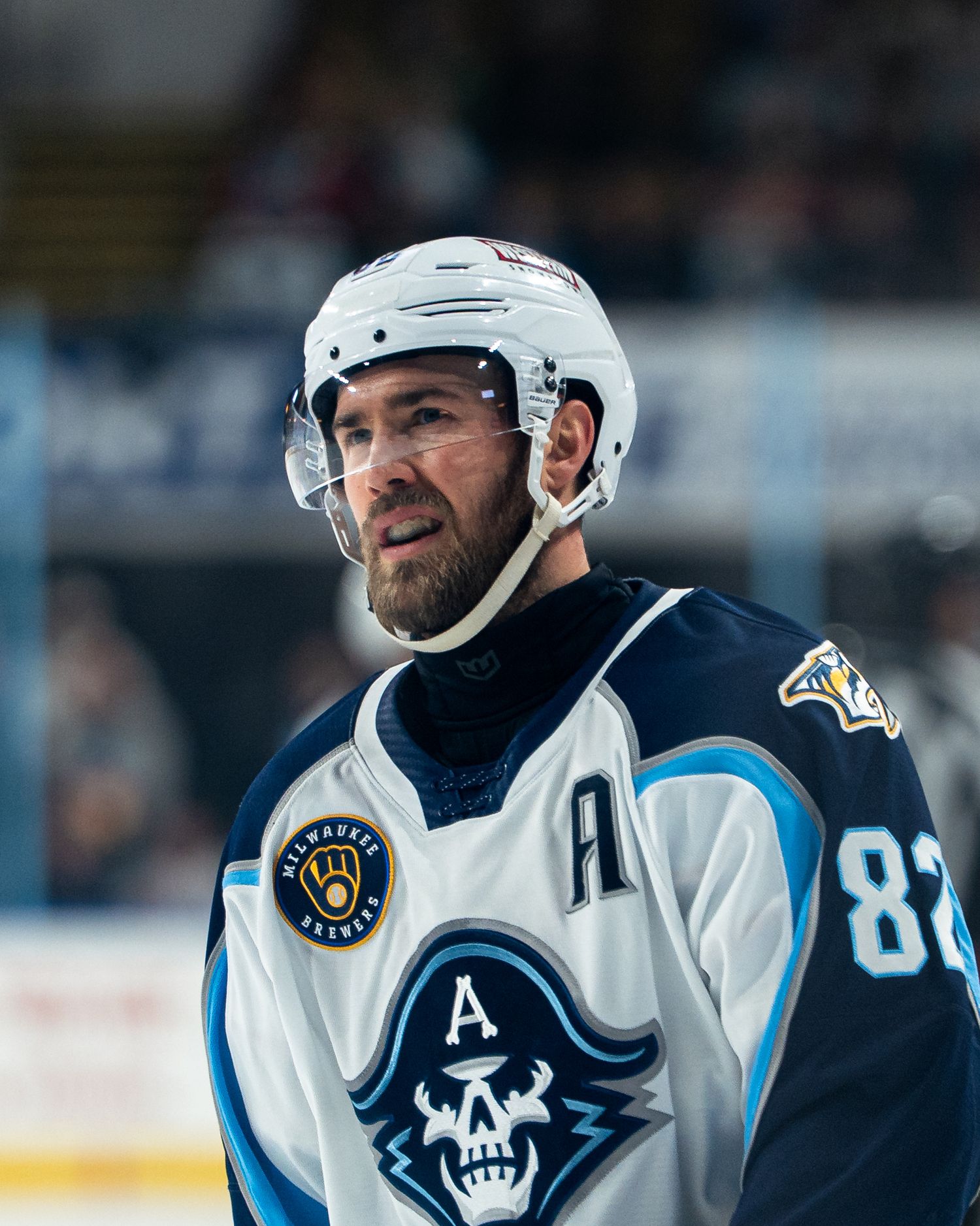 Professional hockey players in white jerseys with skull logo during a game.
