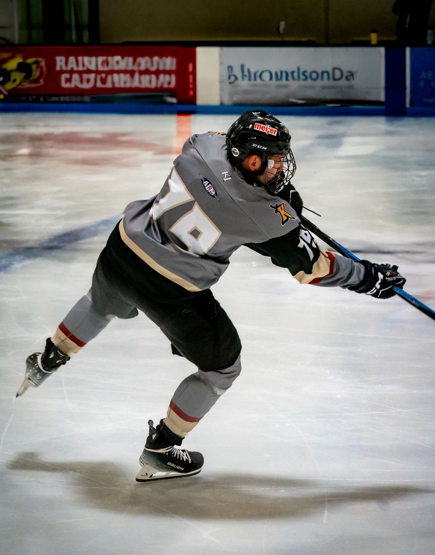 Hockey player in gray jersey executes dynamic skating move on ice during competitive game.