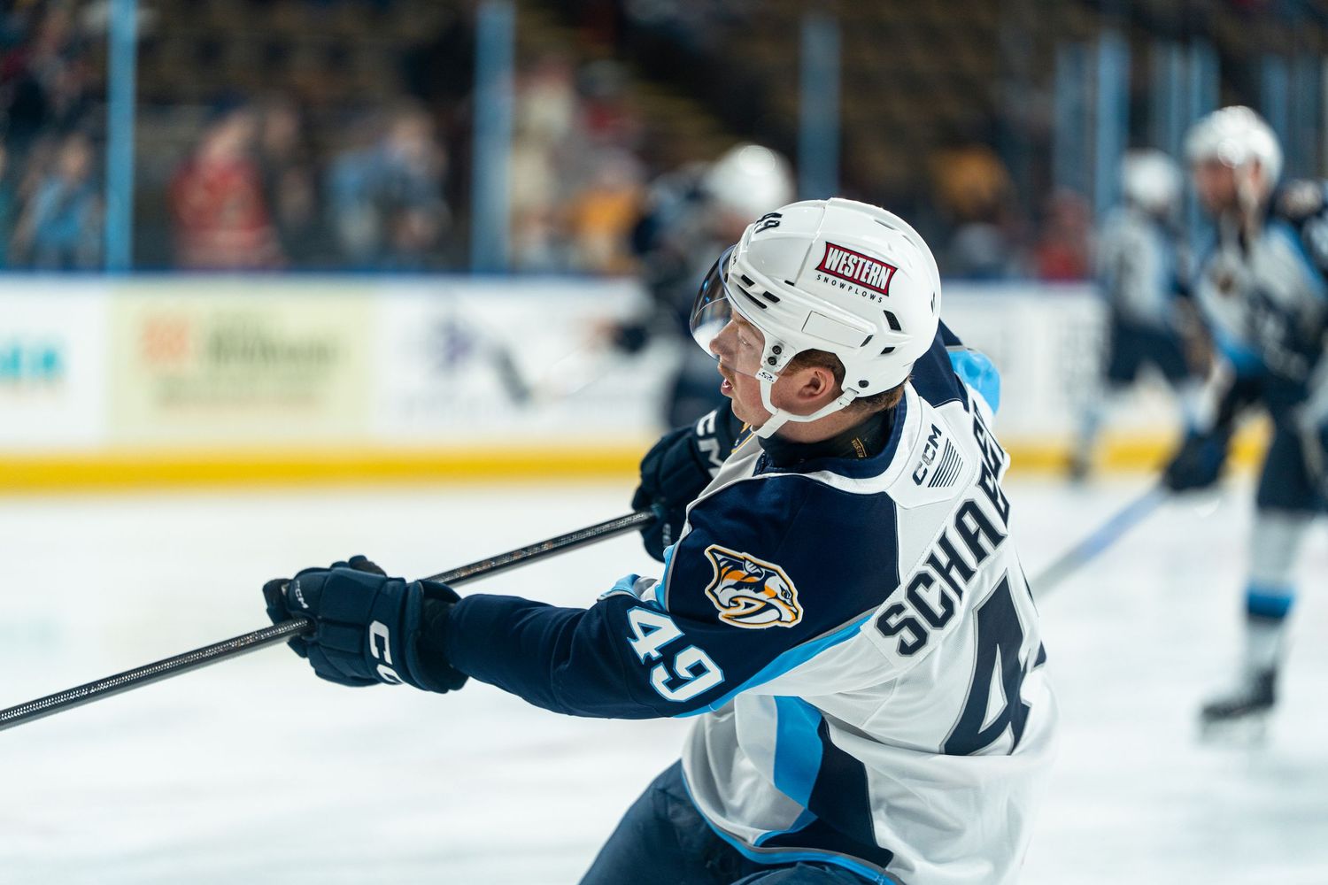 Hockey players in white and dark jerseys battle for the puck during an intense game moment.