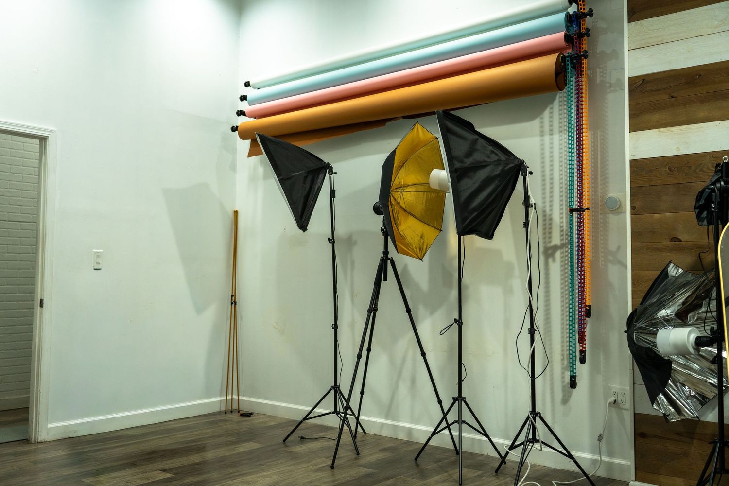 Professional photography studio setup with lighting equipment, white backdrop, and various modifiers arranged in a clean space.