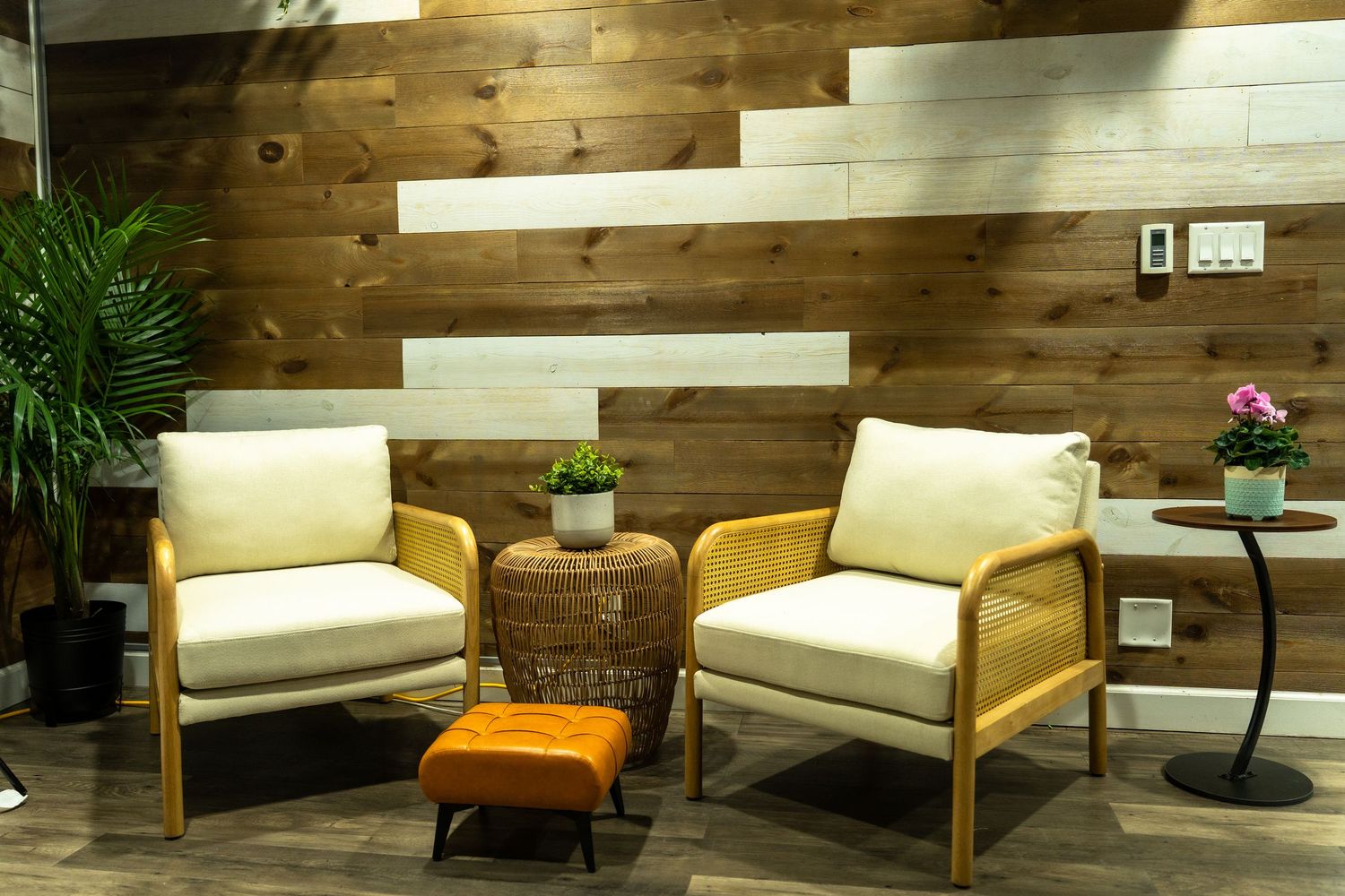 Modern wooden furniture set featuring white cushioned sofas and orange accent chairs against rustic wood paneled walls.