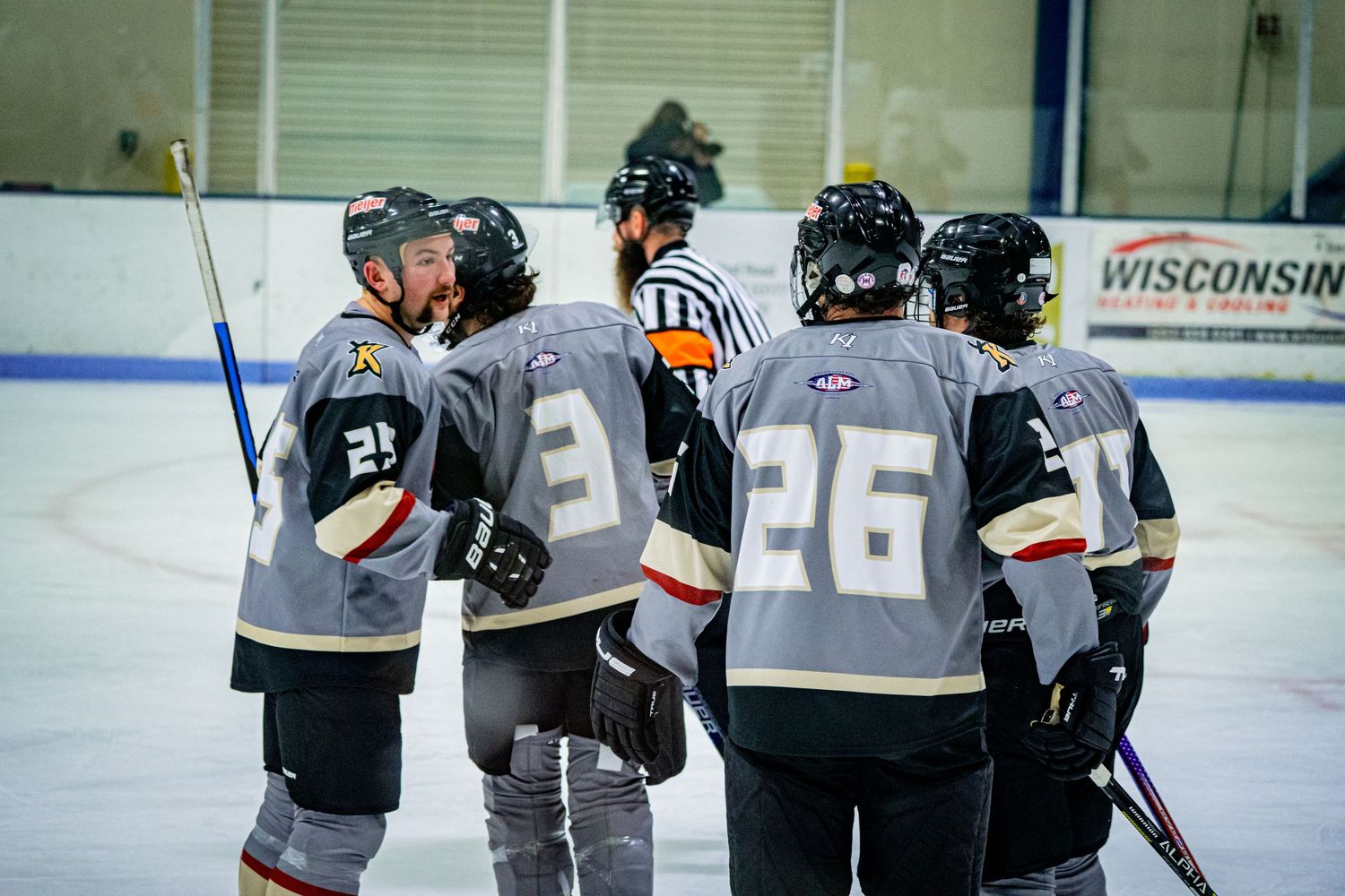 Hockey teammates in matching uniforms gather together on the ice during practice or a game.