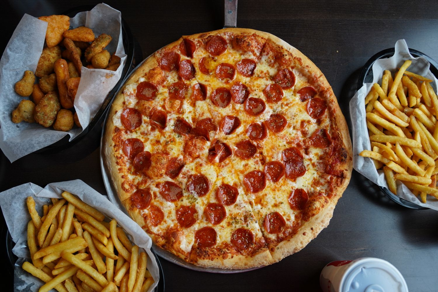 Pepperoni pizza and french fries served in takeout containers.
