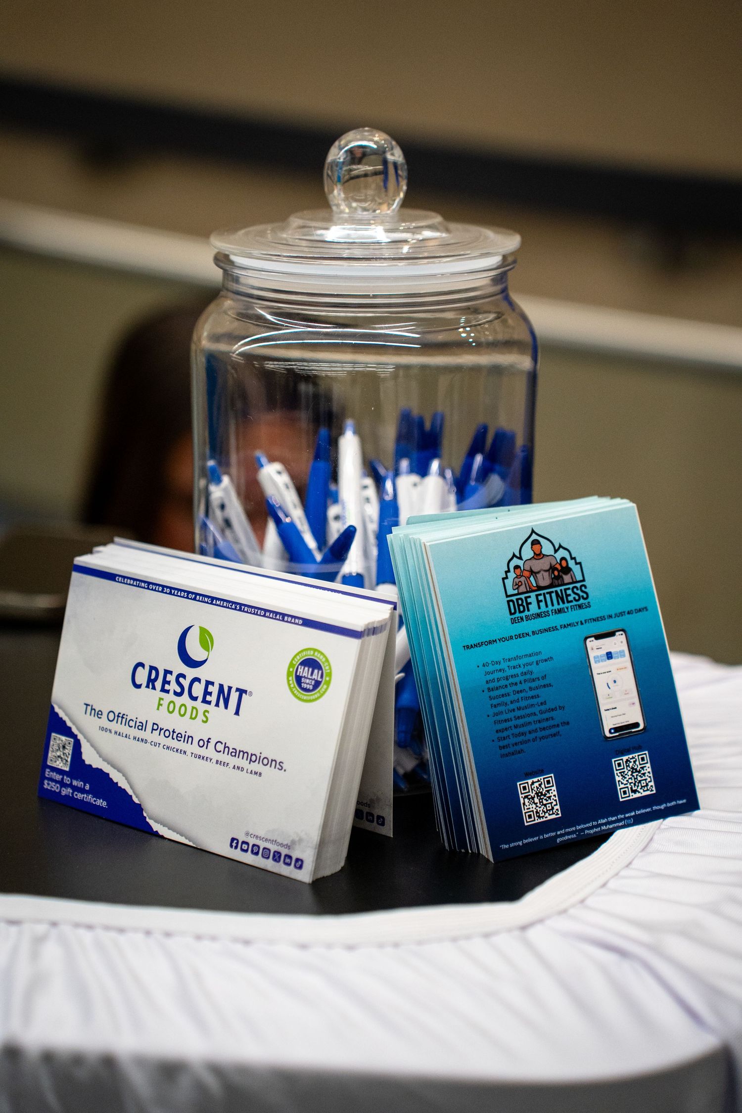 Business cards and contact information displayed in glass jars on a white tablecloth at a networking event.