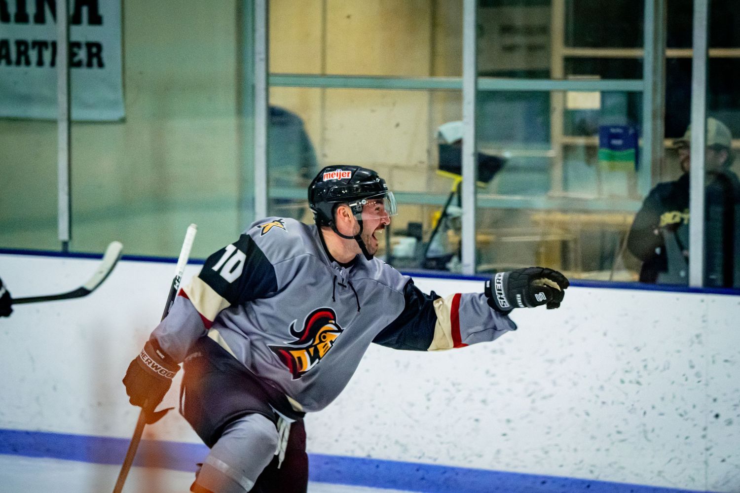 Hockey player glides across ice during training drill at indoor arena.