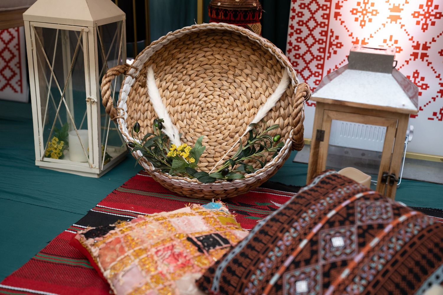 Decorative woven baskets and red and white patterned textiles displayed on a teal colored table surface.