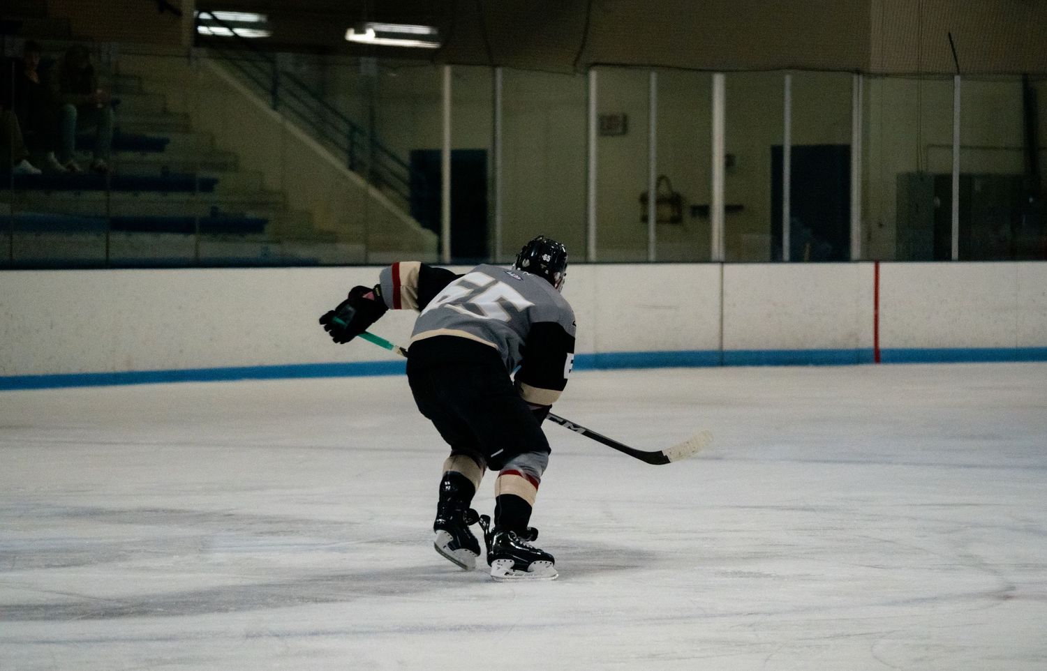 Multiple hockey players glide across a brightly lit indoor ice rink during a game.