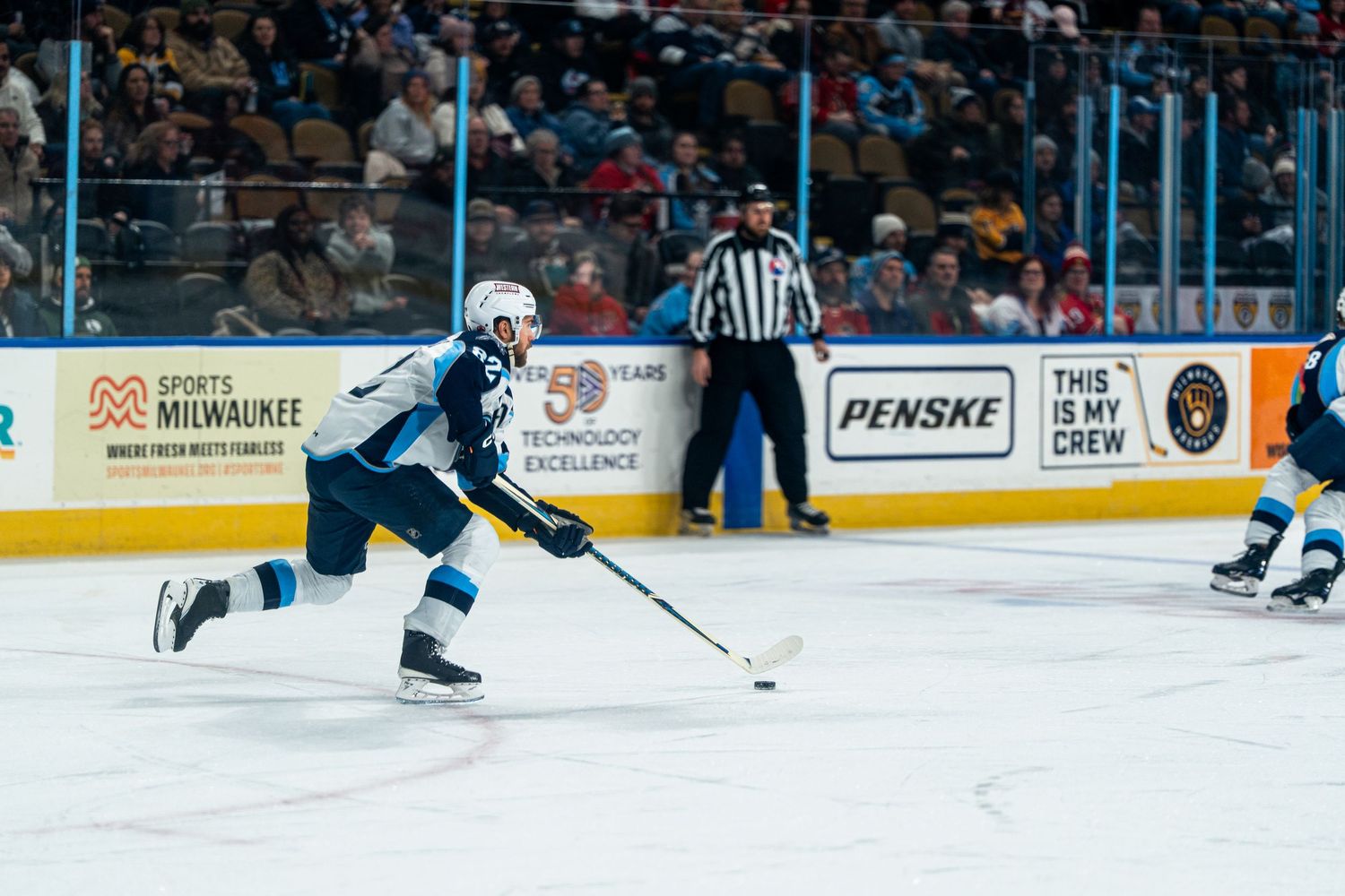 Wide shot of a hockey game showing players skating across the ice rink.