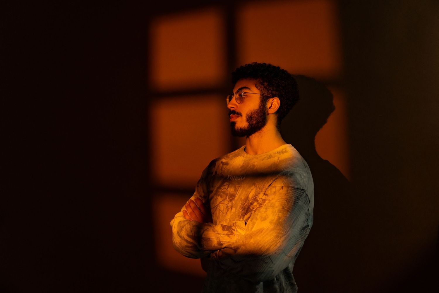 A person performs an expressive dance move against a dark background with dramatic lighting and shadows.