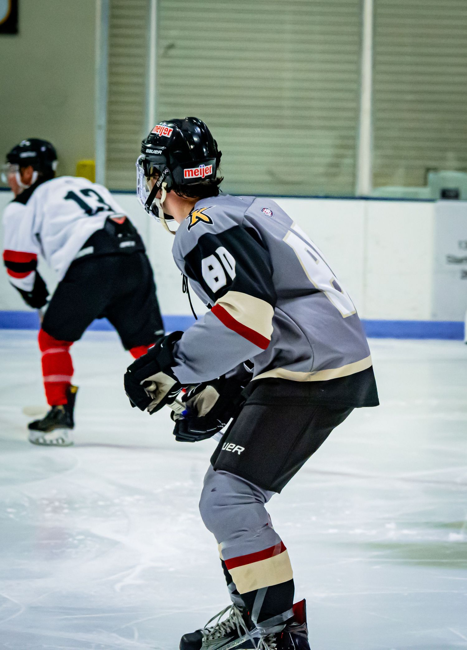 Hockey player in gray jersey positions themselves during gameplay on the ice.